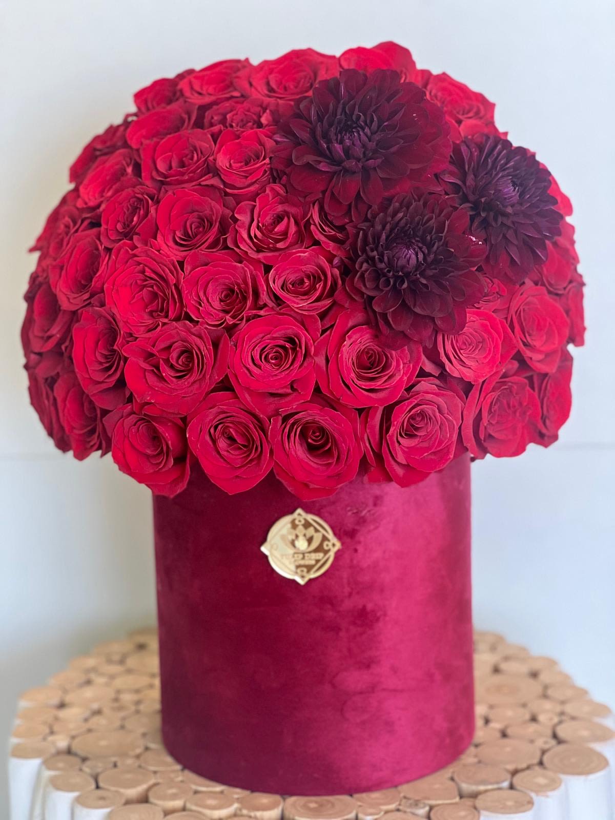Red rose bouquet in a velvet hatbox with dark burgundy flowers