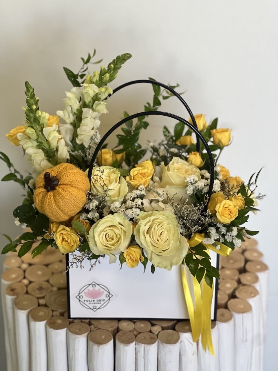 Yellow and cream roses arranged in a white gift box with a small knitted pumpkin