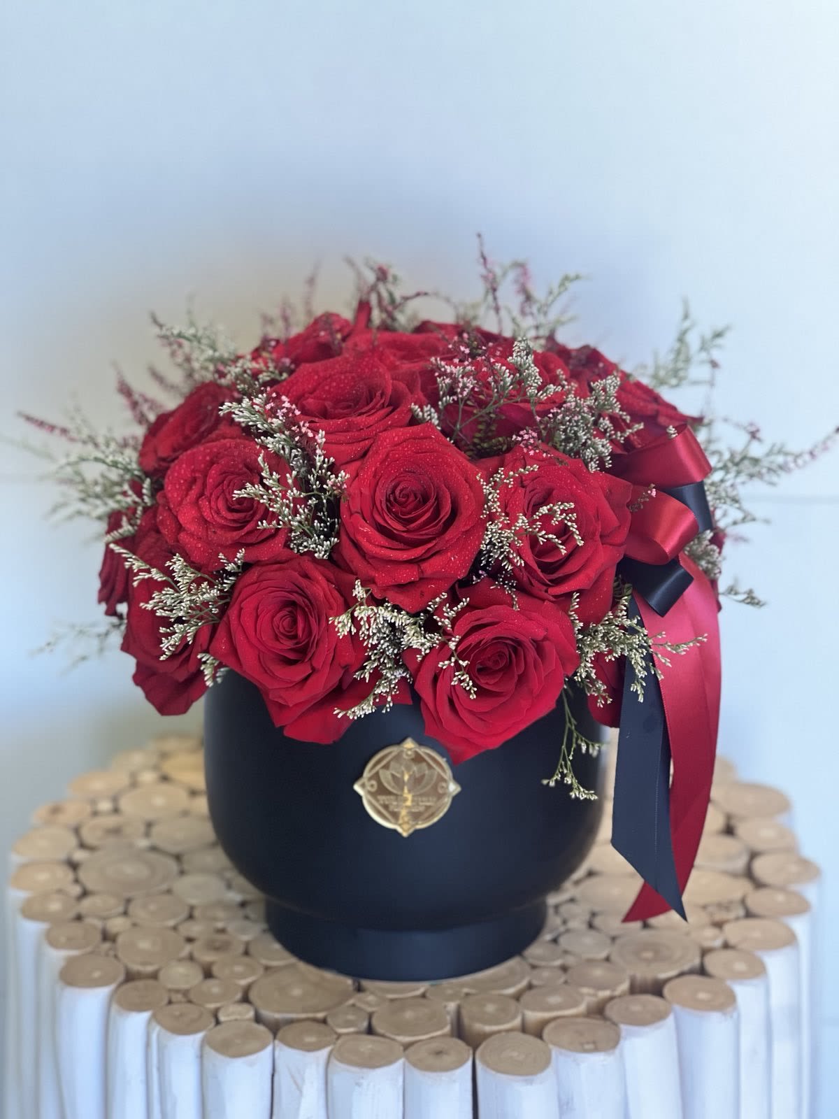 Red roses arranged in a black round box with ribbon