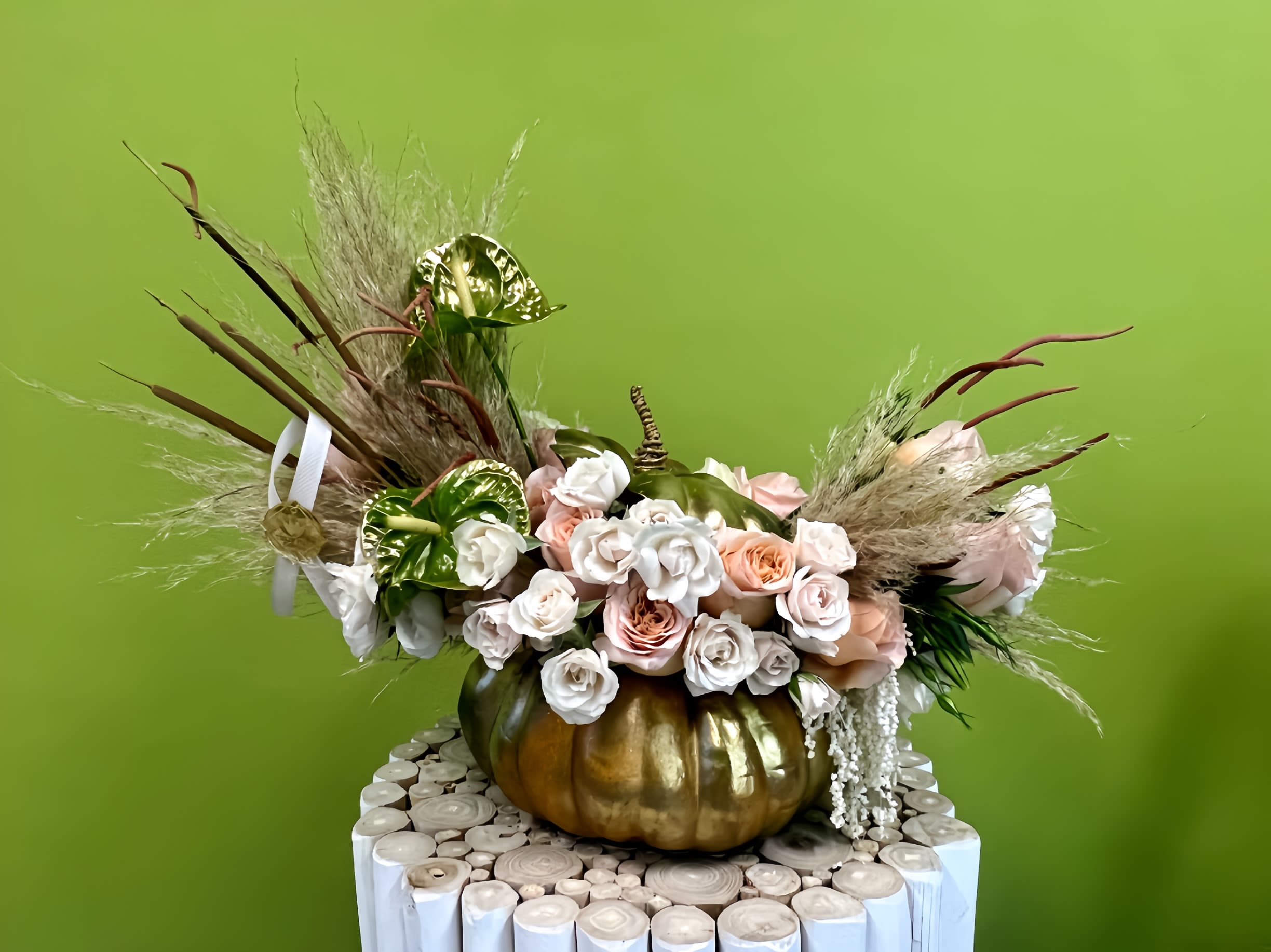 Floral arrangement with roses and anthuriums in a gold pumpkin container