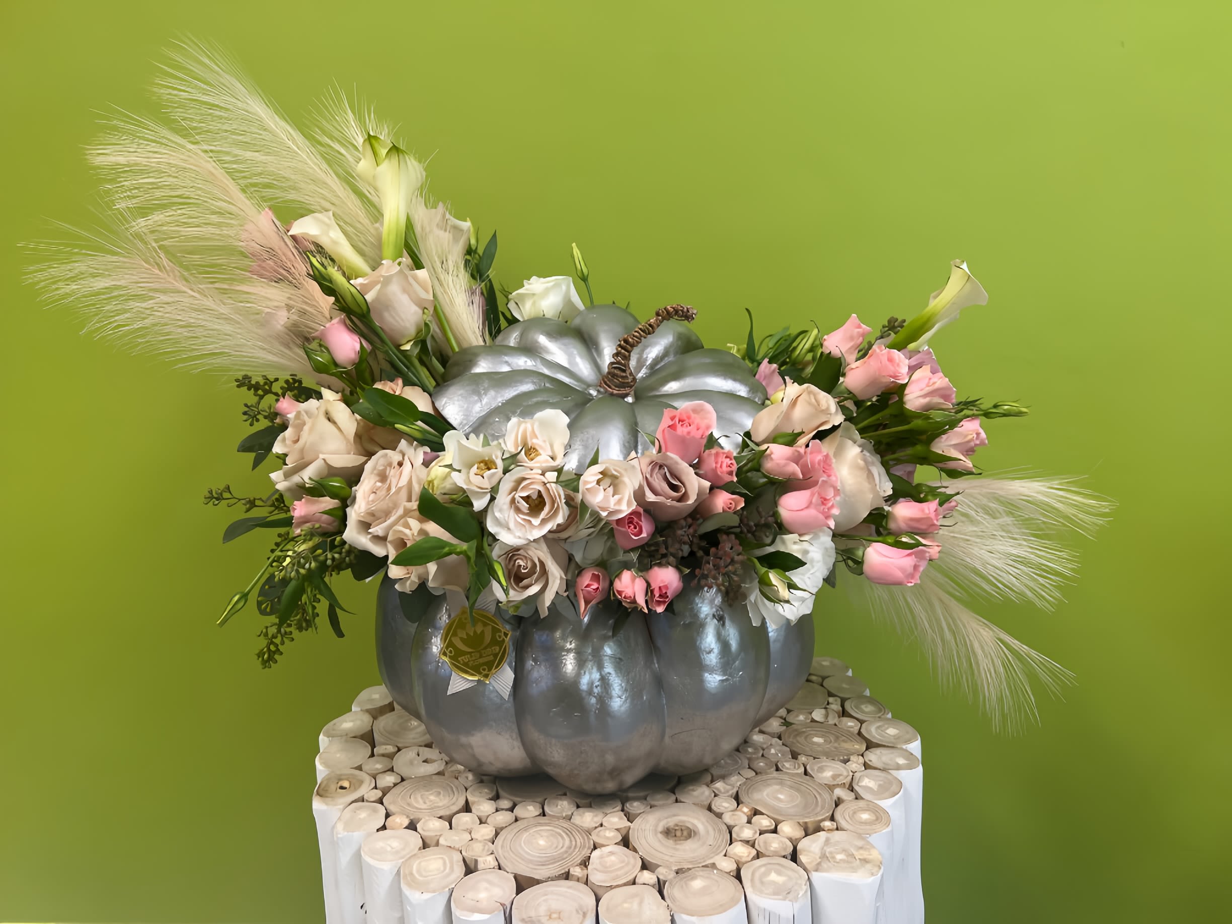 Pink and white flowers arranged in a silver pumpkin container