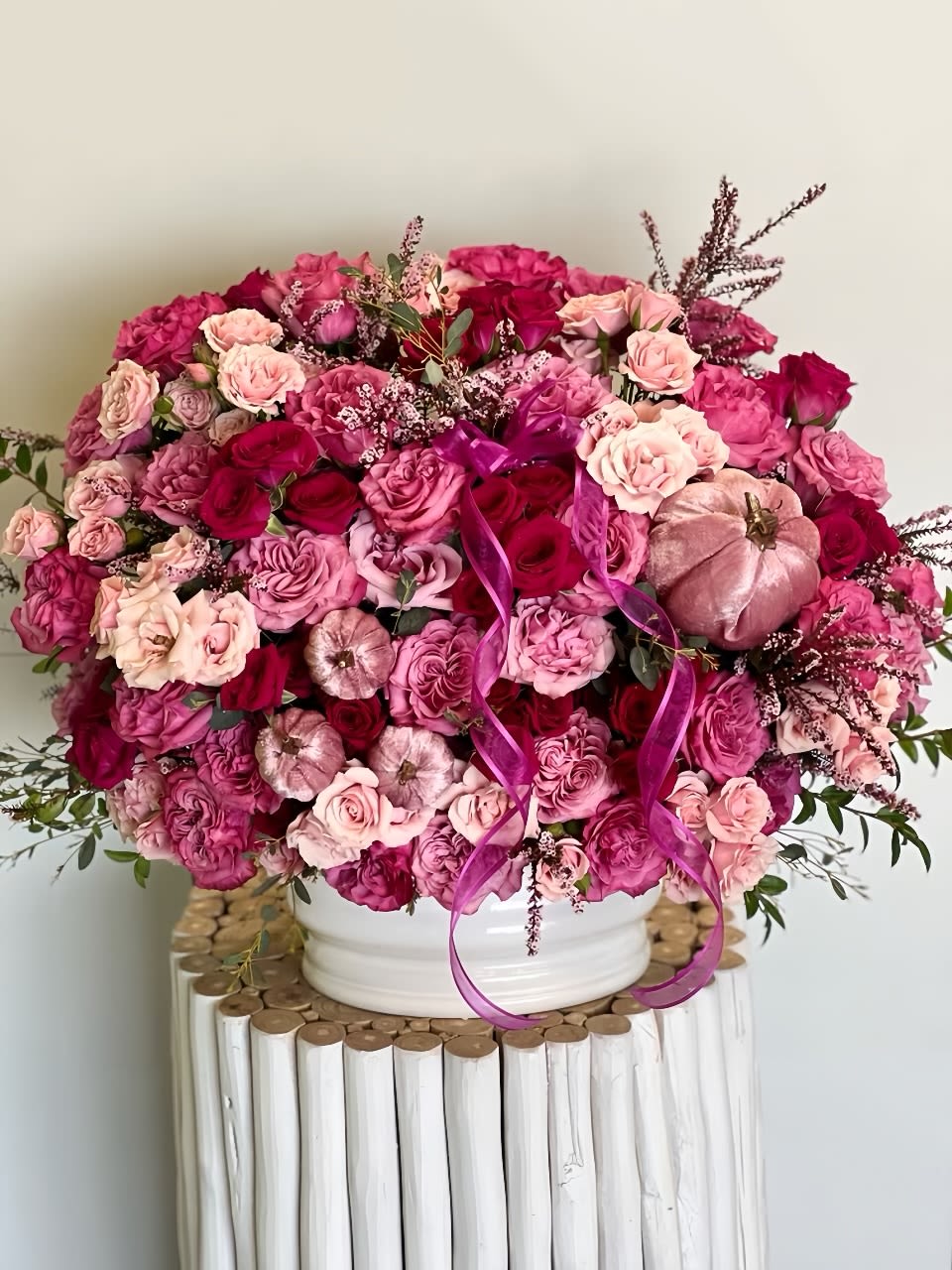 Large pink and magenta rose arrangement in a white vase