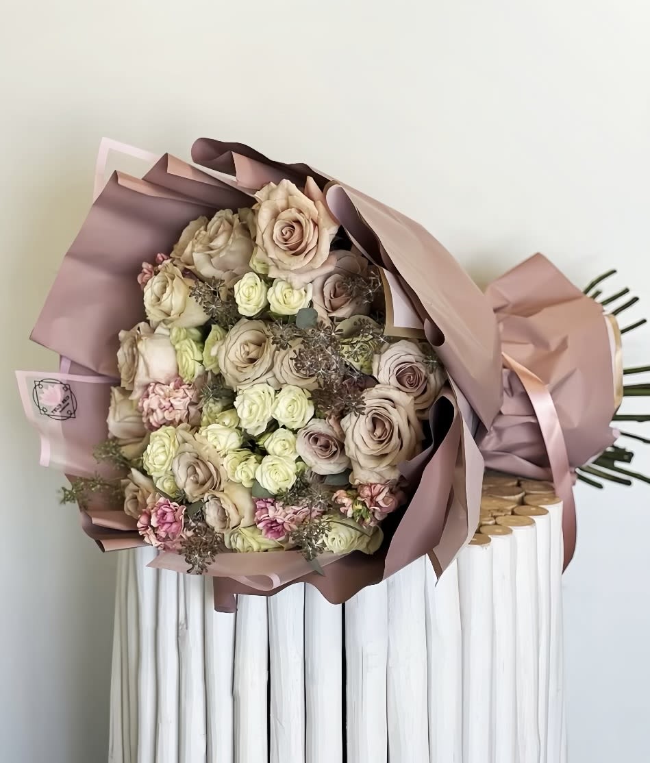 Bouquet of blush and cream roses wrapped in pink paper