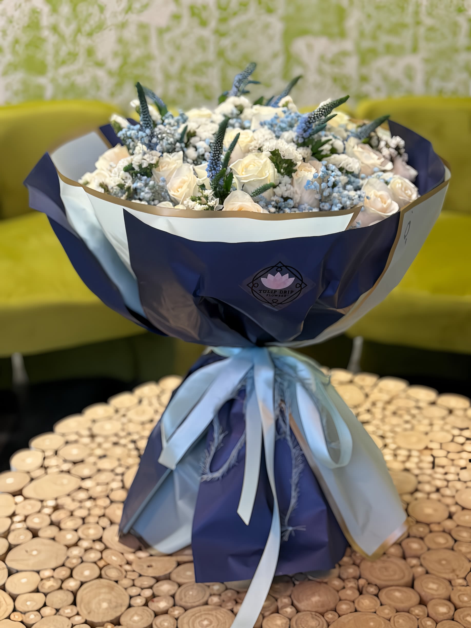 Bouquet of white roses and blue flowers wrapped in navy and white paper