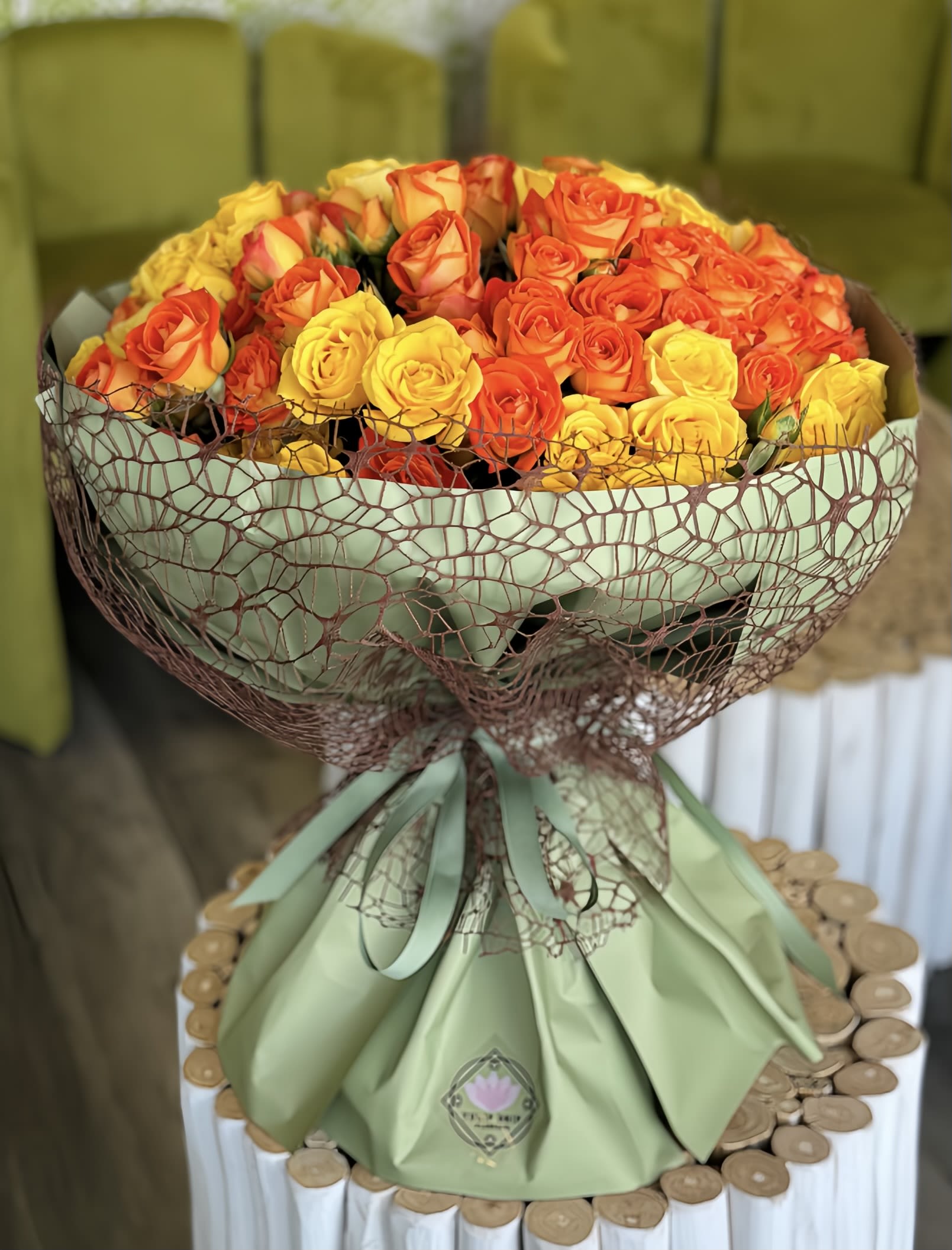 Bouquet of orange and yellow roses wrapped in green paper