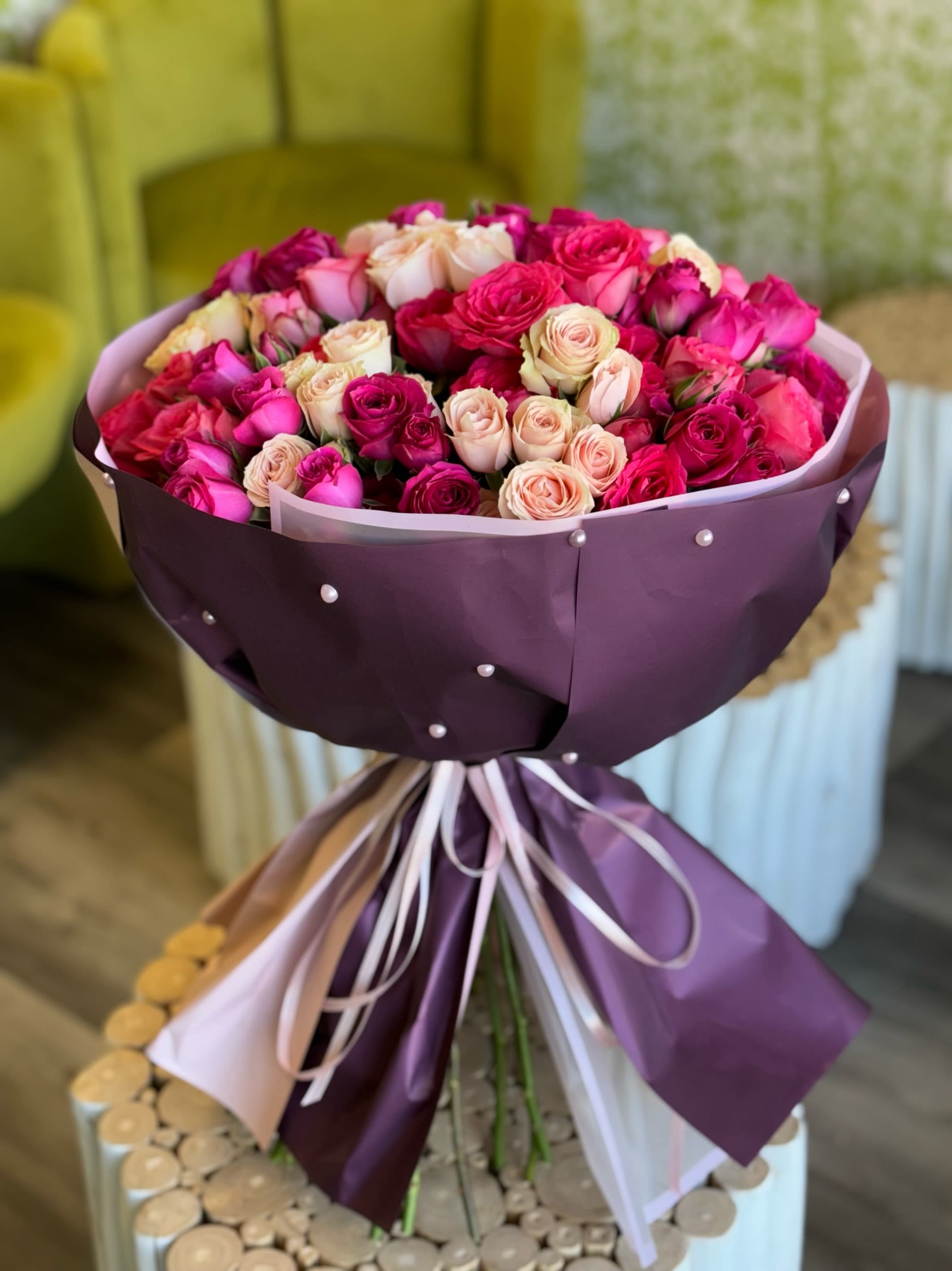 Bouquet of pink and cream roses wrapped in purple paper