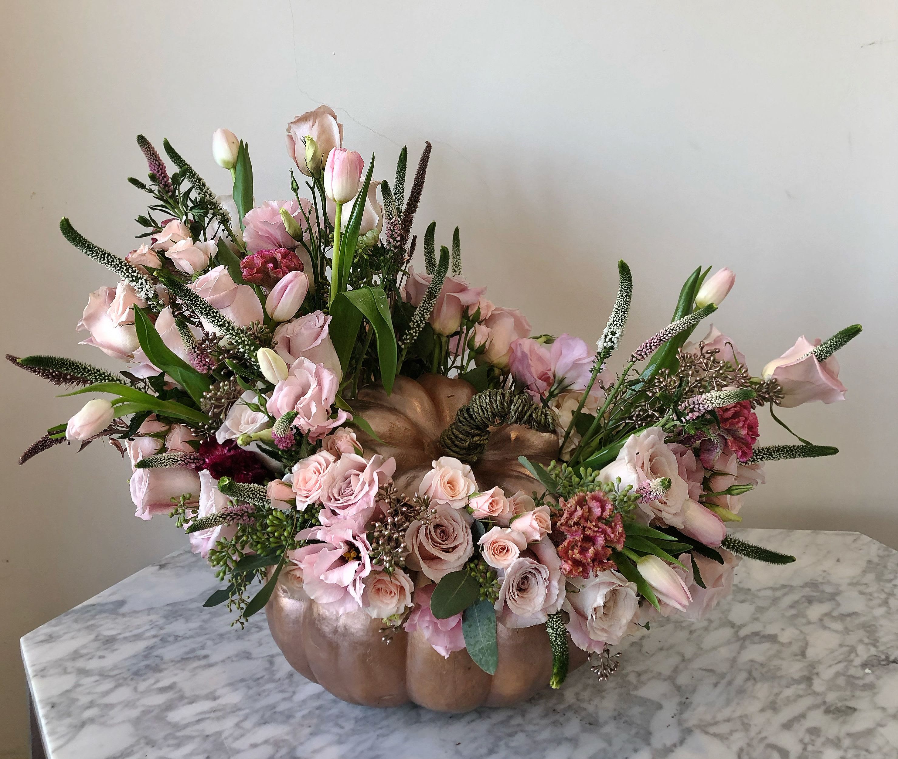 Pink floral arrangement in a pumpkin-shaped vase