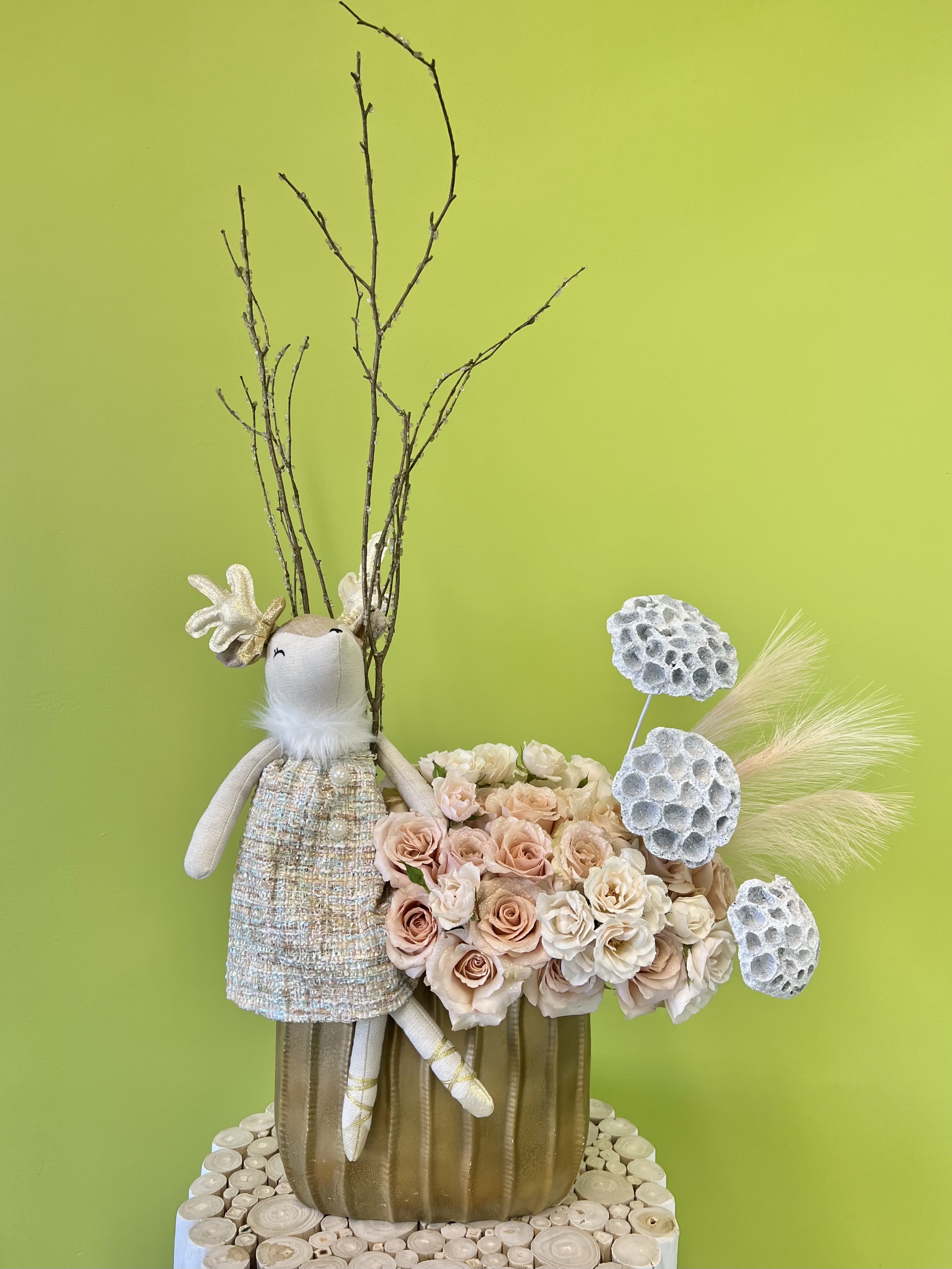Floral arrangement with blush roses and a decorative bunny figure in a gold vase