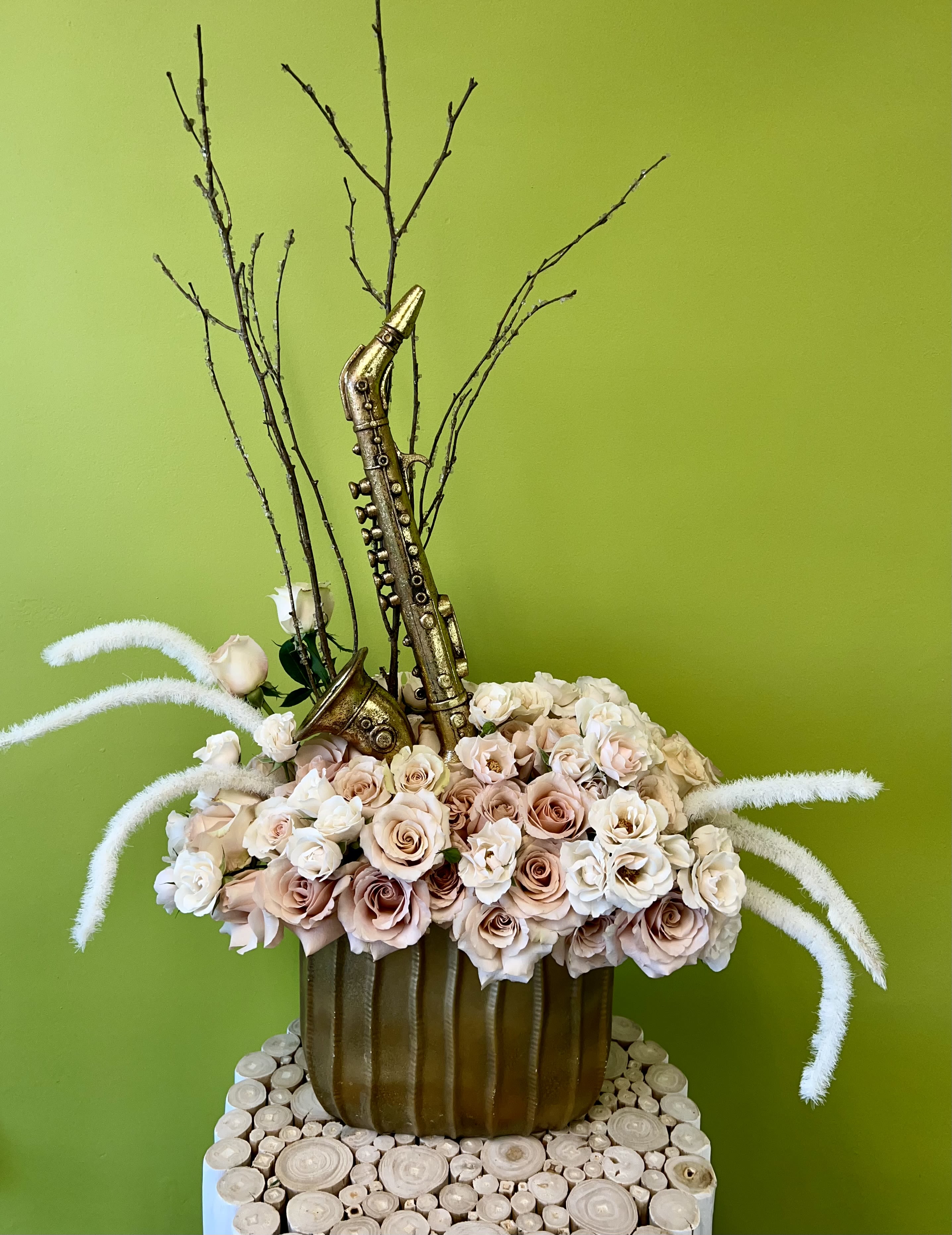 Arrangement of pale roses with a gold saxophone decoration in a brown vase