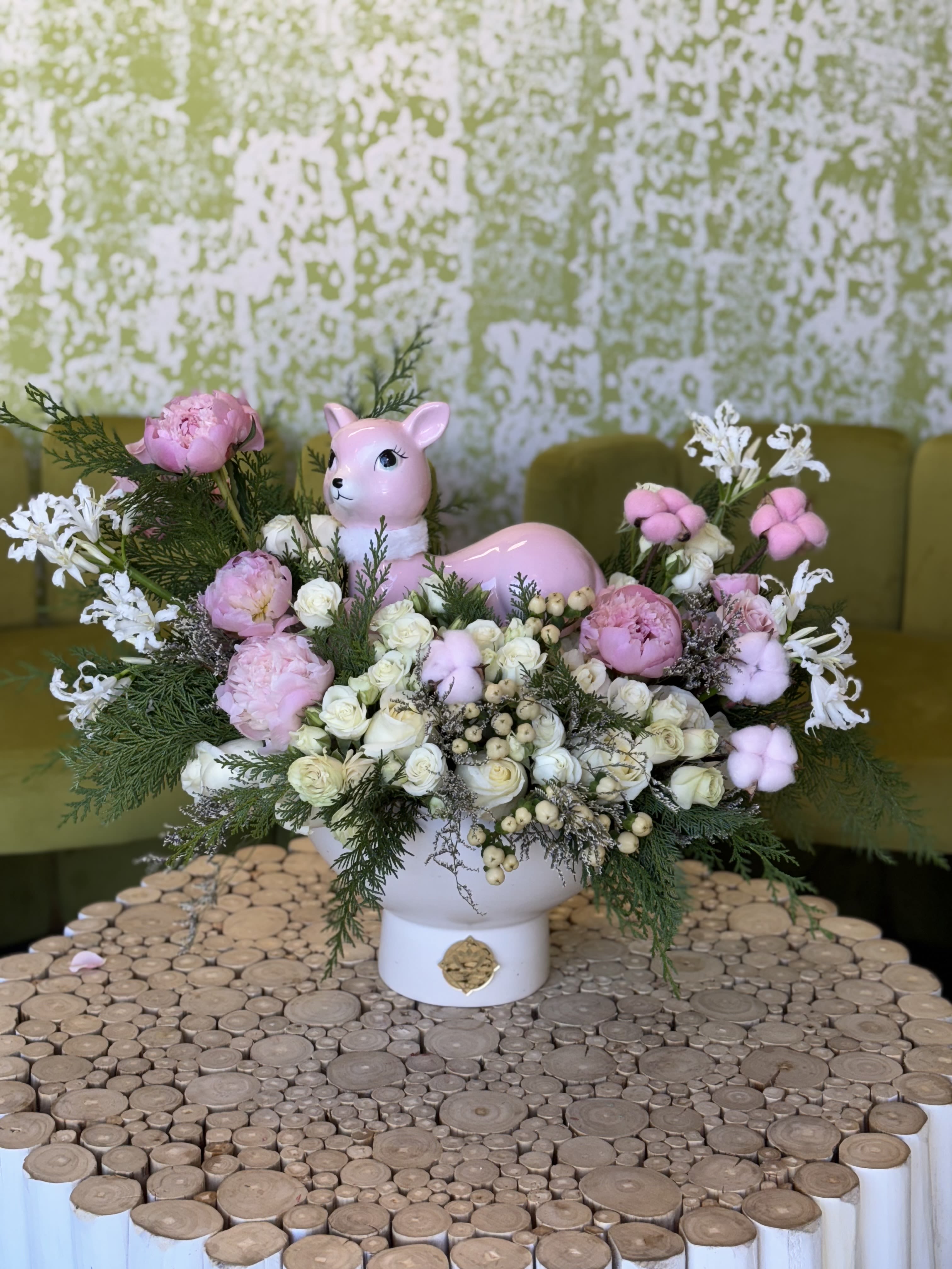 Pink deer figurine surrounded by pink and white flowers in a white vase