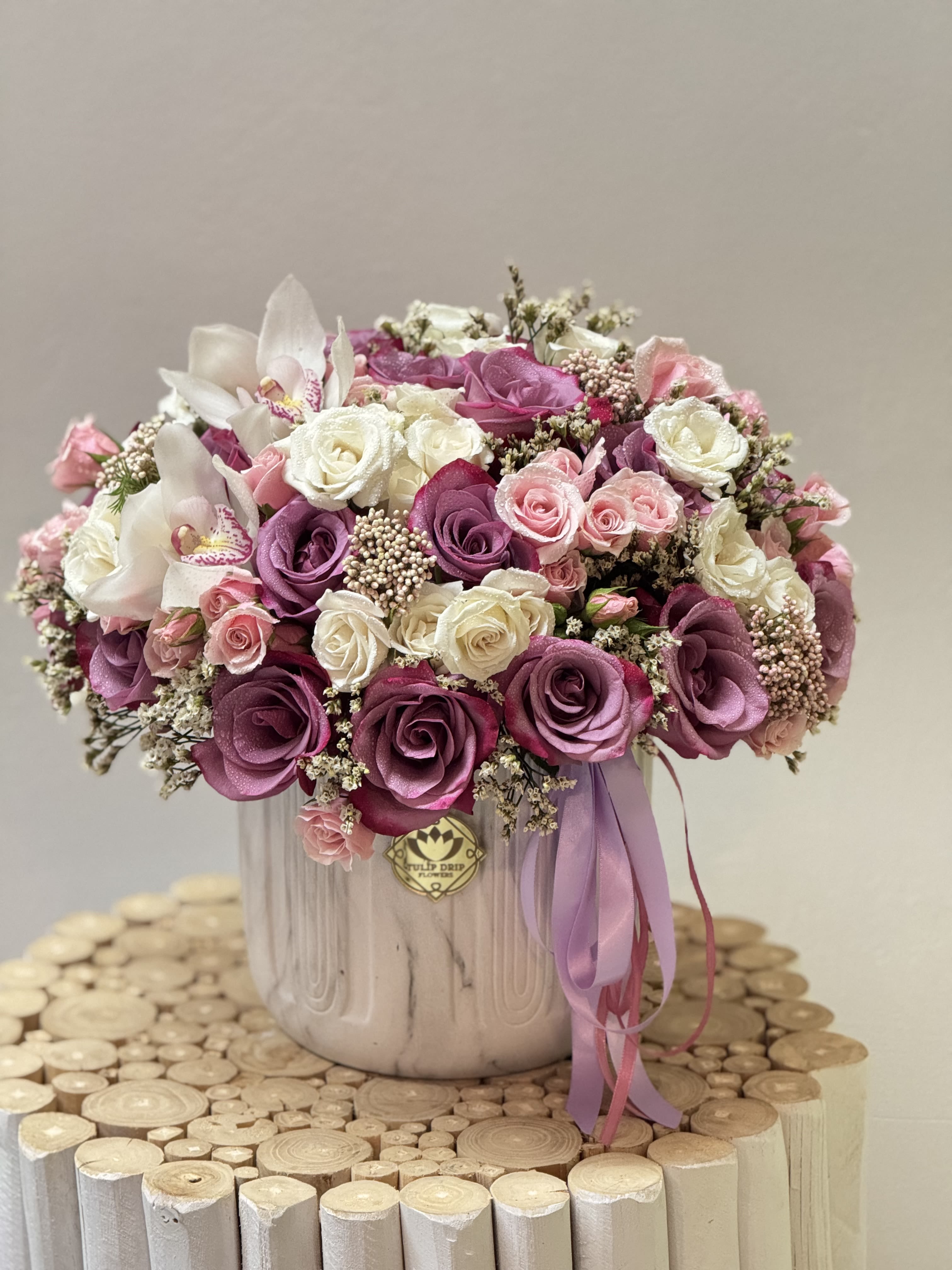 Pink and white rose arrangement in a ceramic vase with a ribbon