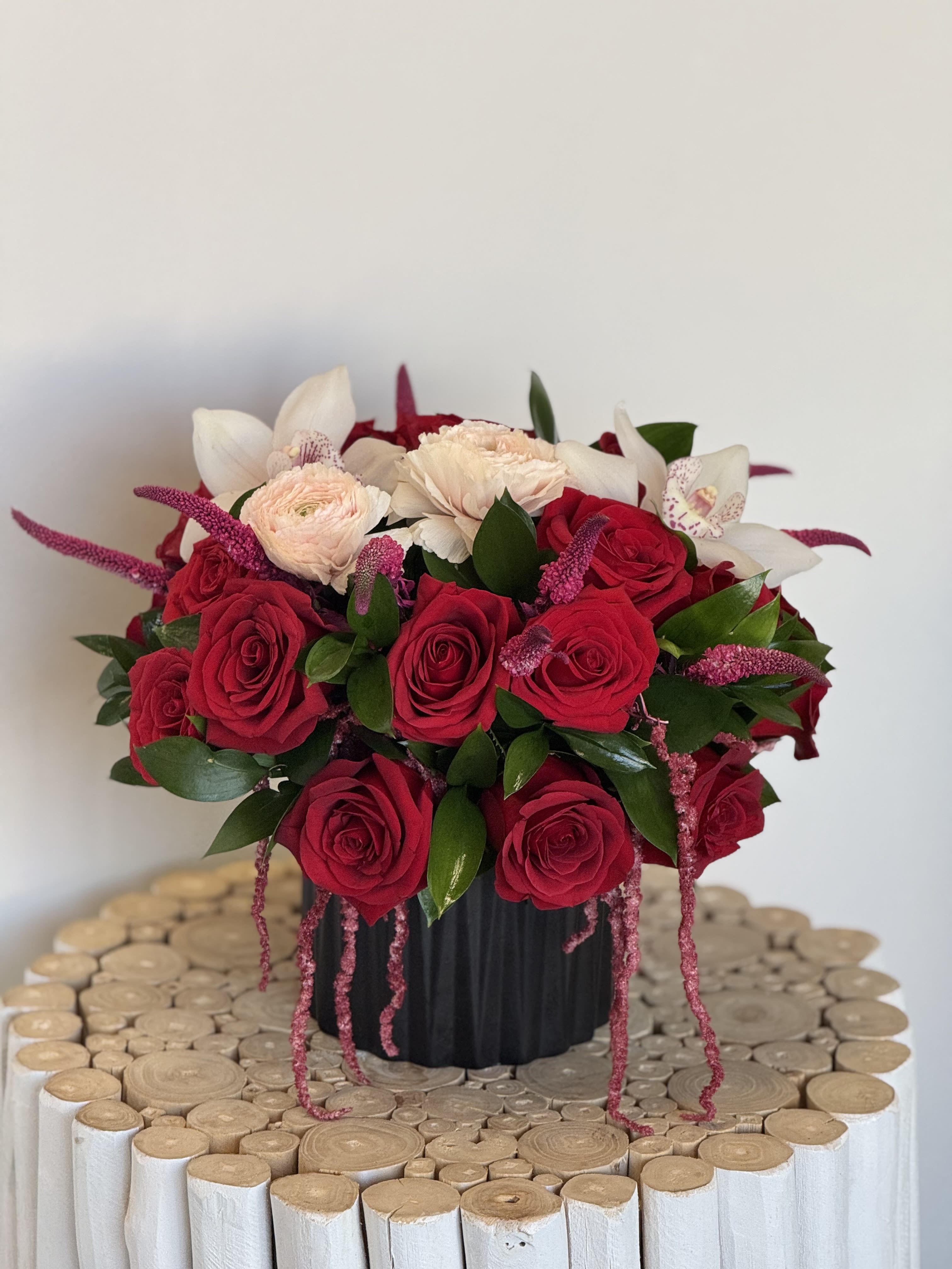 Red and white rose arrangement in a black vase