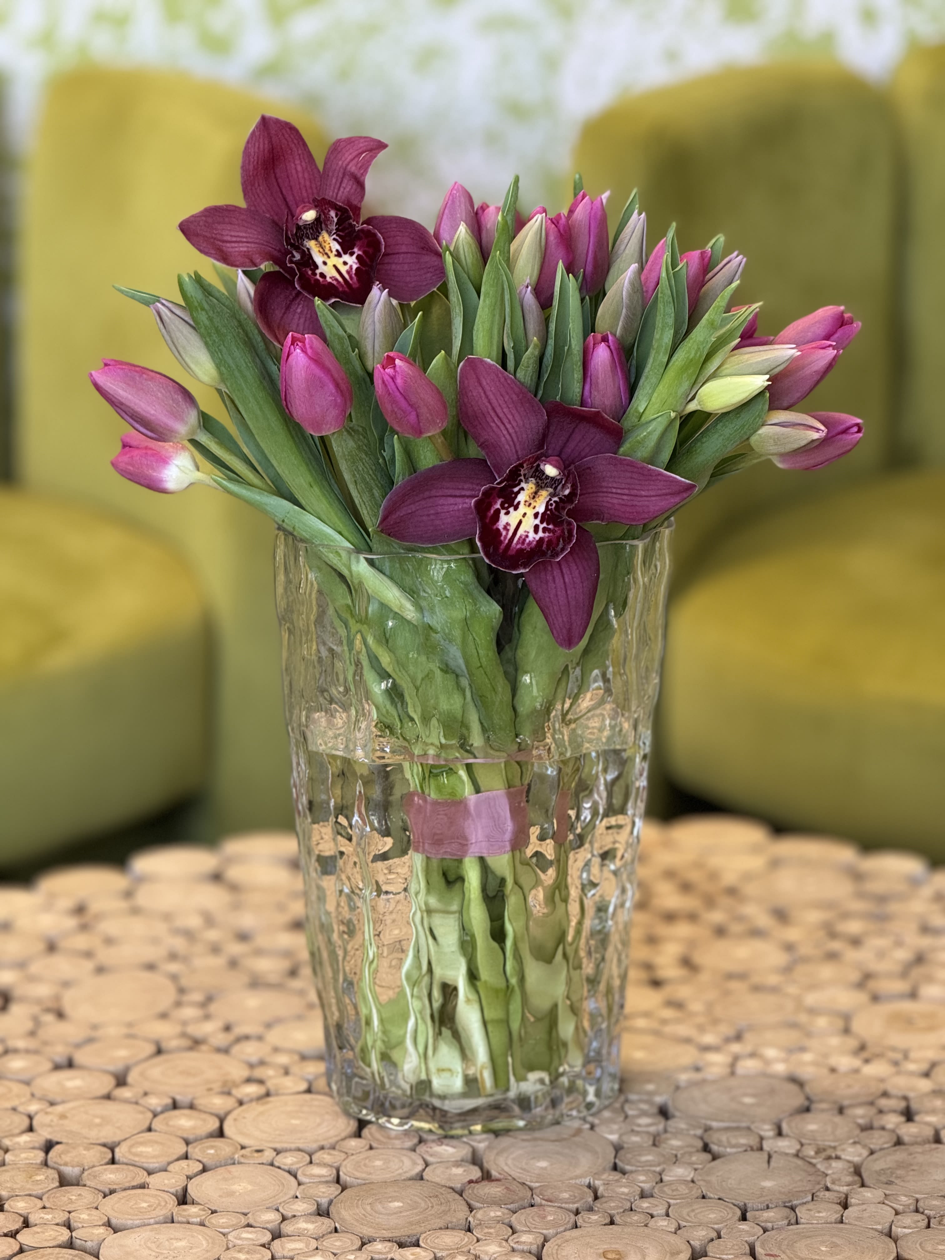 Purple orchids and pink tulips in a clear glass vase