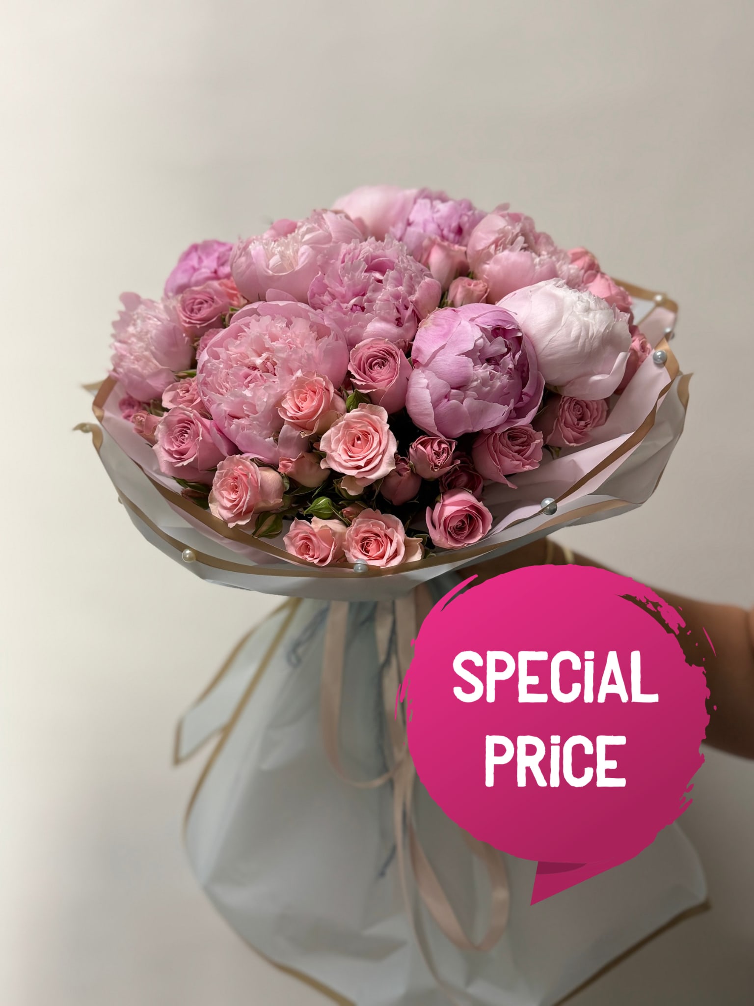 Pink bouquet of peonies and roses wrapped in pale paper