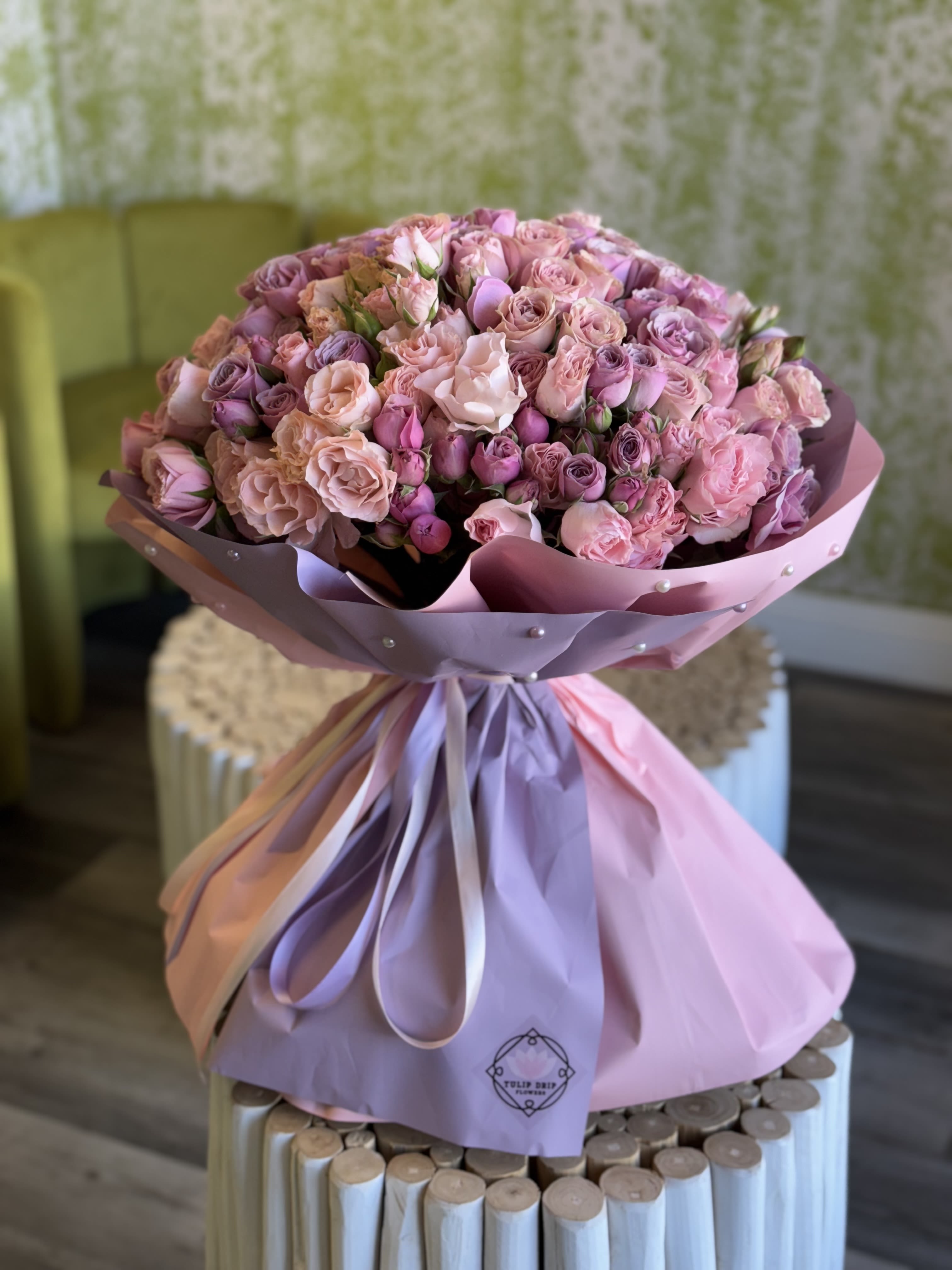 Large bouquet of pink and lavender roses wrapped in pastel paper