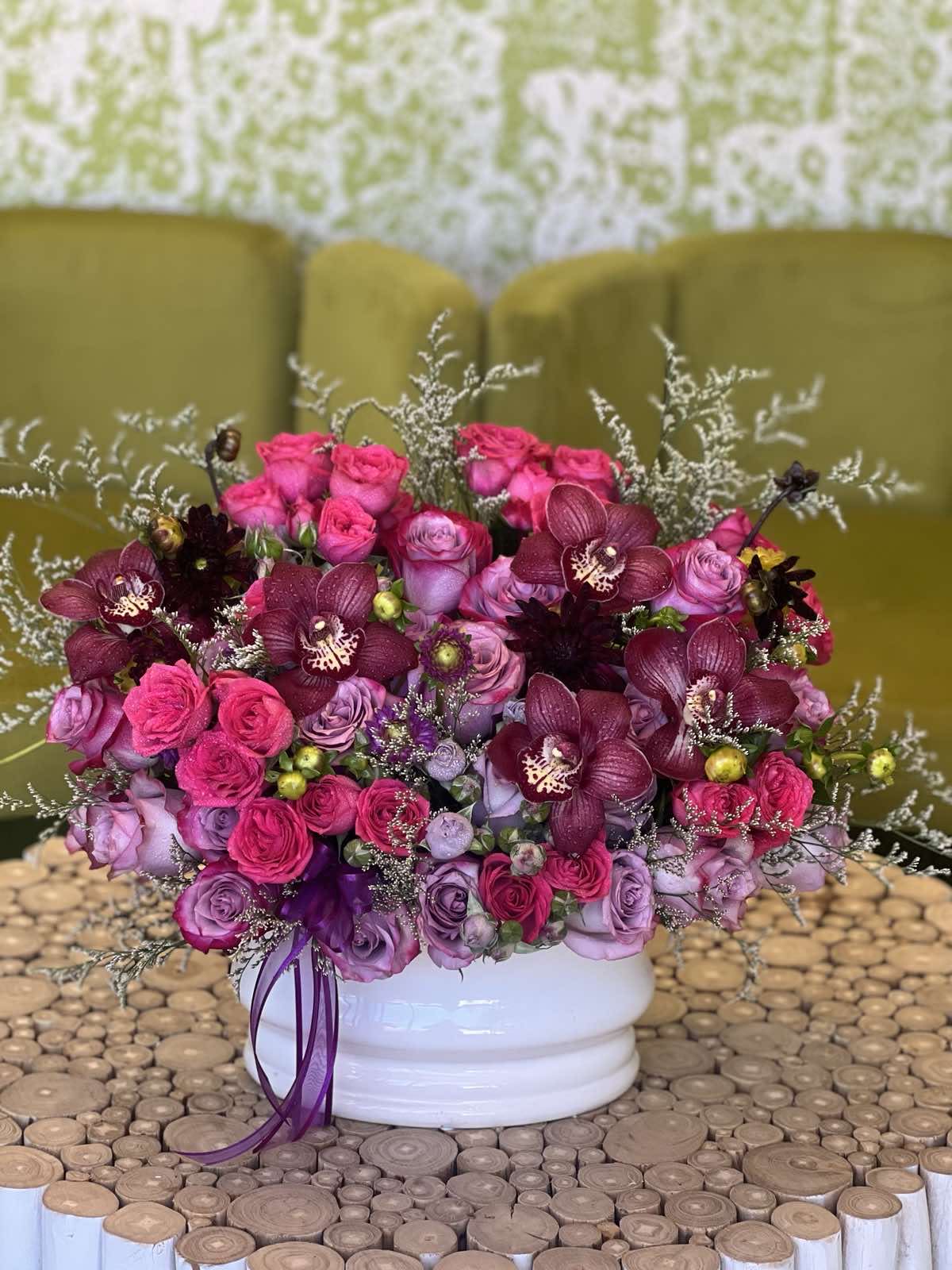 Pink and purple rose bouquet with dark orchids in a white vase