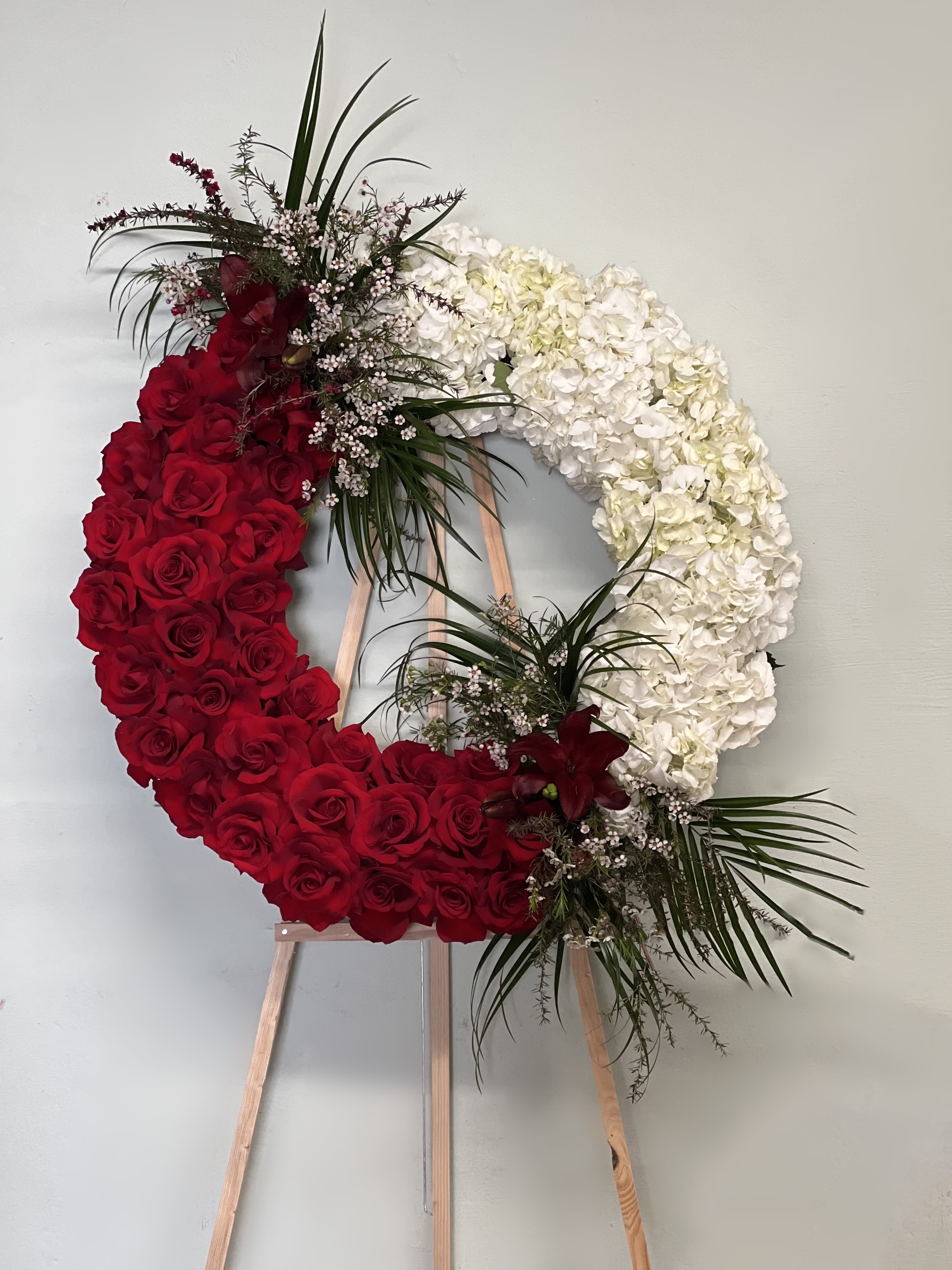 Heart-shaped floral wreath of red roses and white hydrangeas on an easel