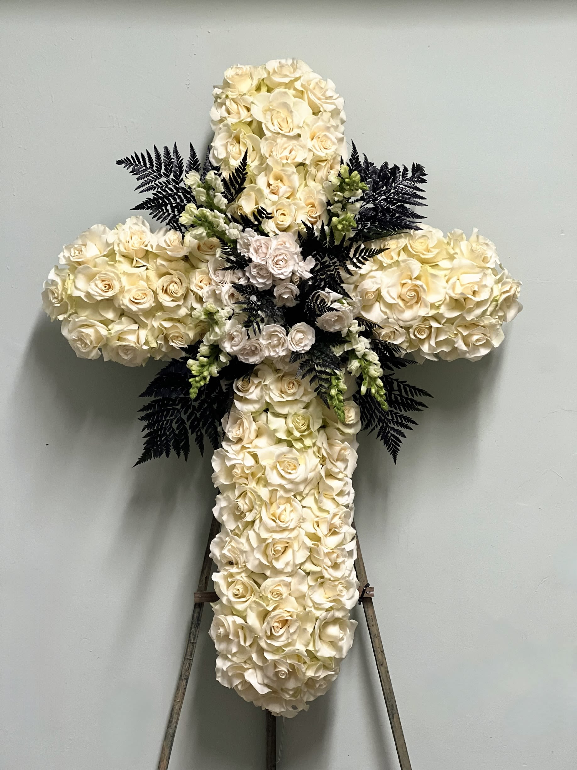 White rose cross-shaped floral tribute on an easel