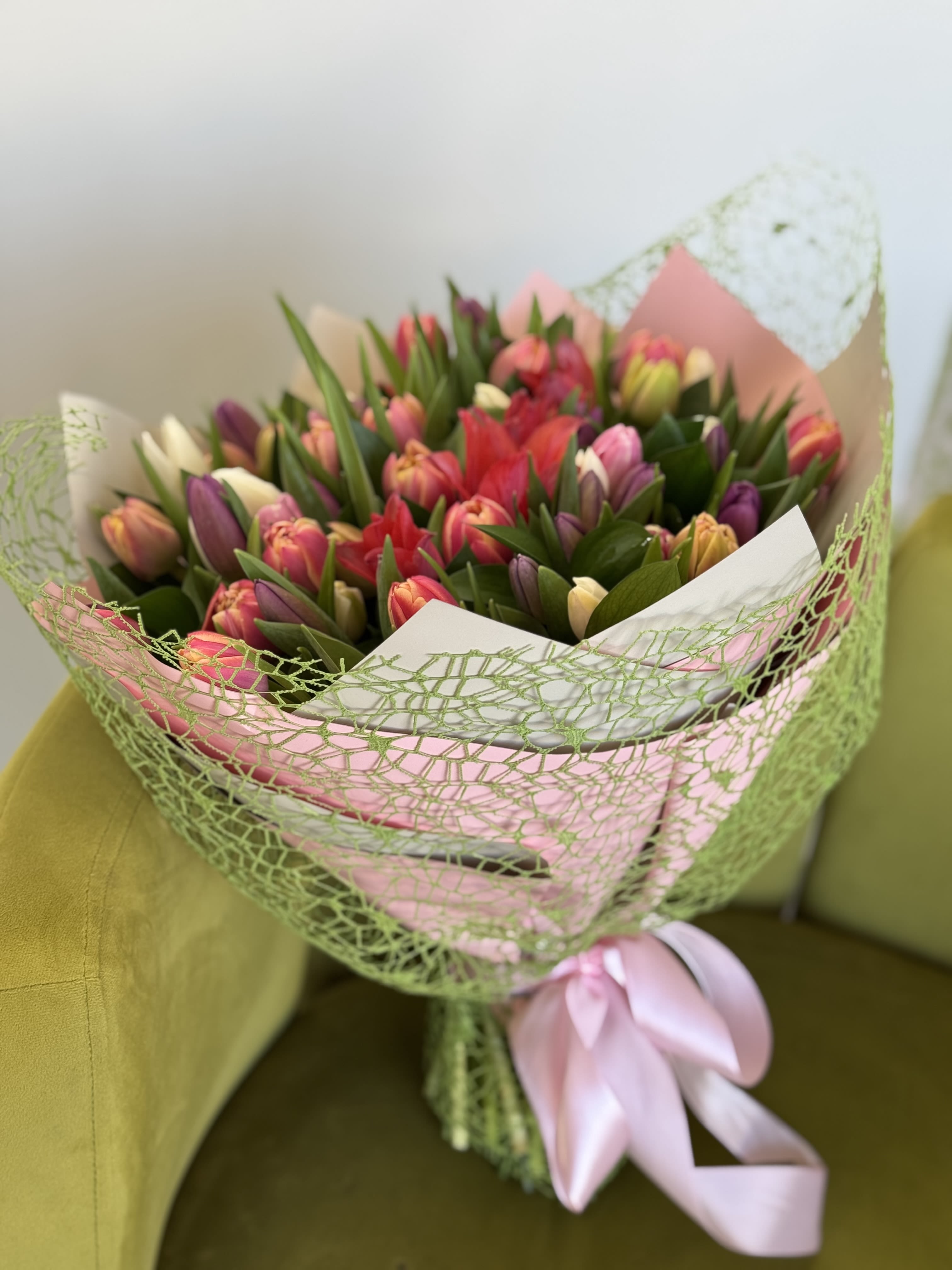 Bouquet of multicolored tulips wrapped in pink and green paper