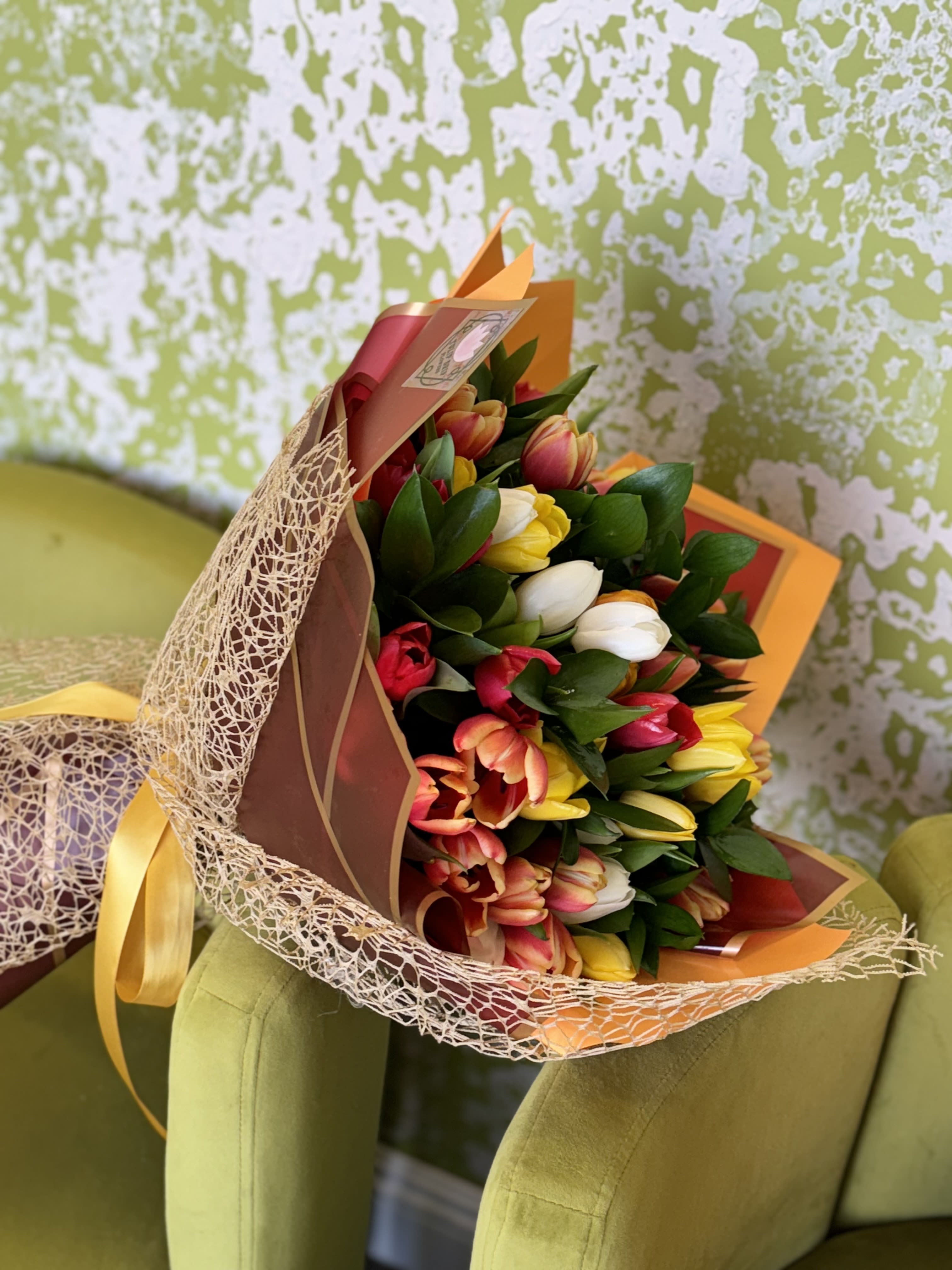 Bouquet of multicolored tulips wrapped in decorative paper and mesh
