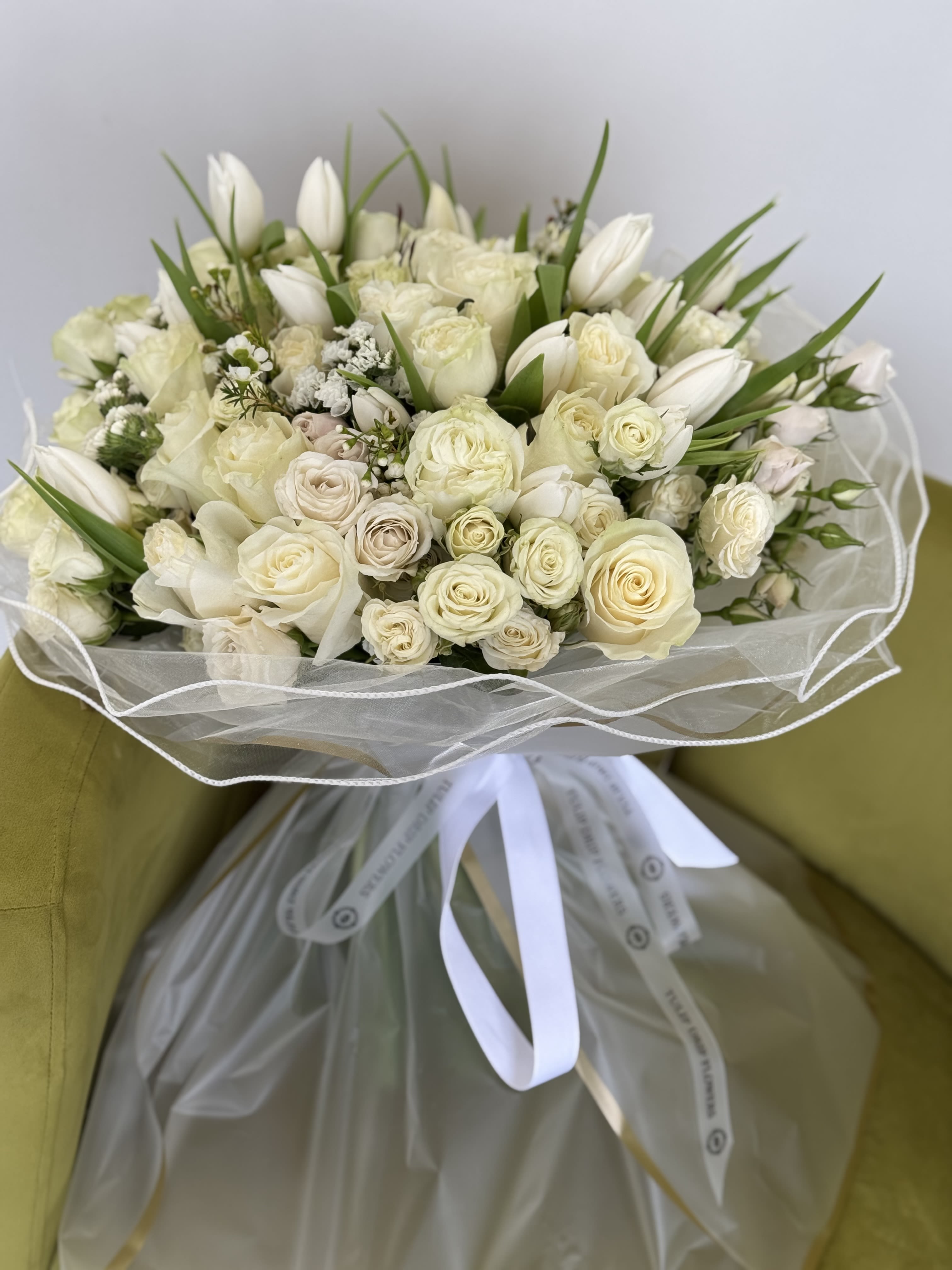 Cream rose and white tulip bouquet wrapped in sheer paper