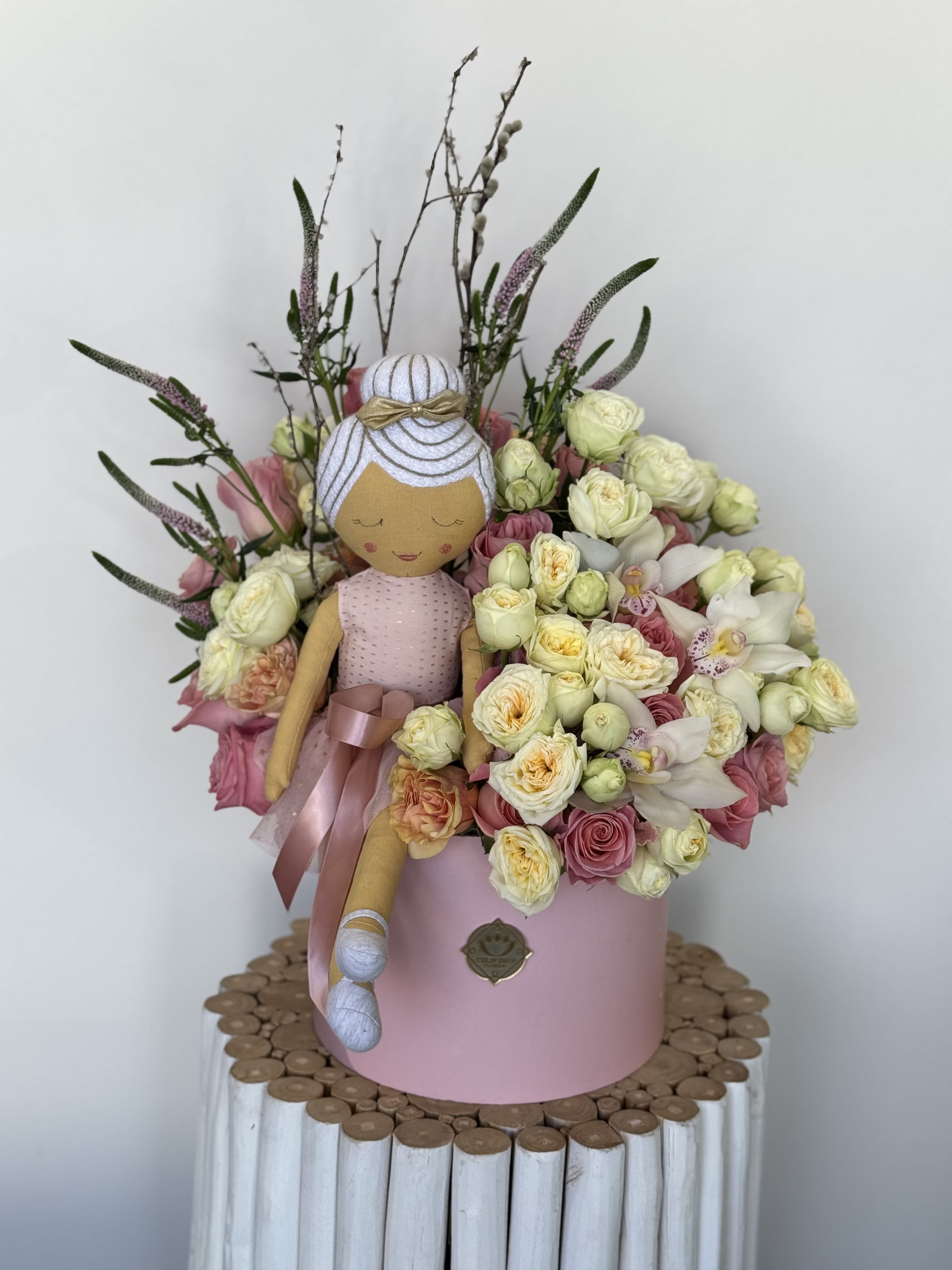 Bouquet with a fabric doll and pink and cream flowers in a pink box