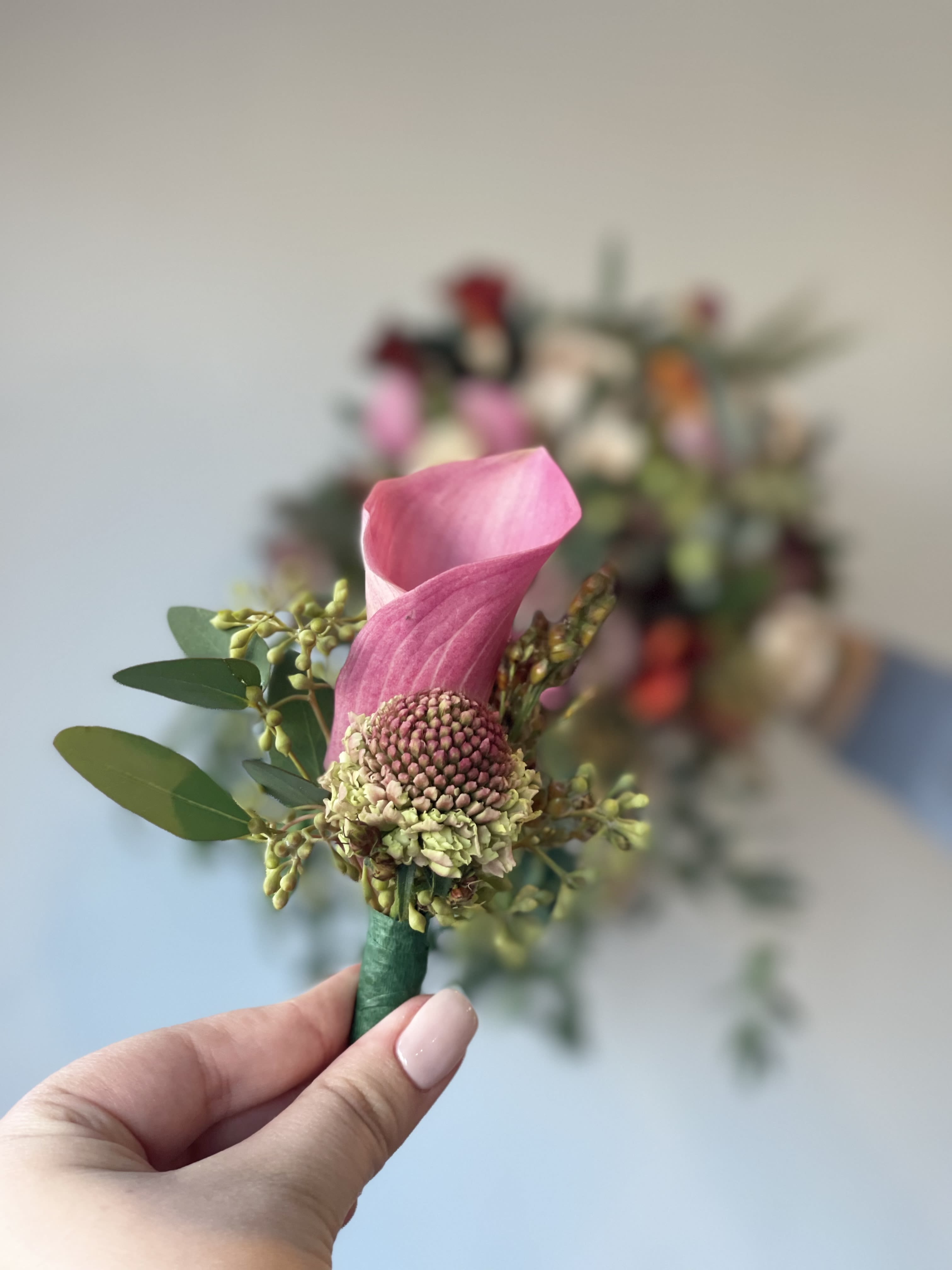 Pink calla lily boutonniere with small green accents