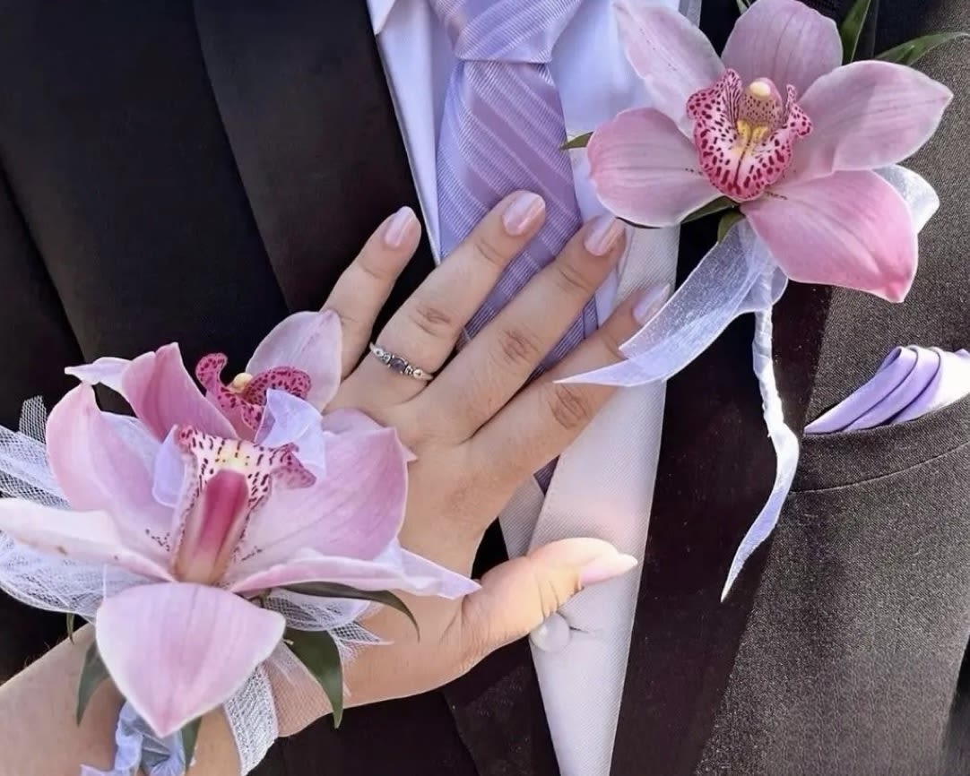 Pink orchid corsage and boutonniere with lavender ribbon on a suit jacket