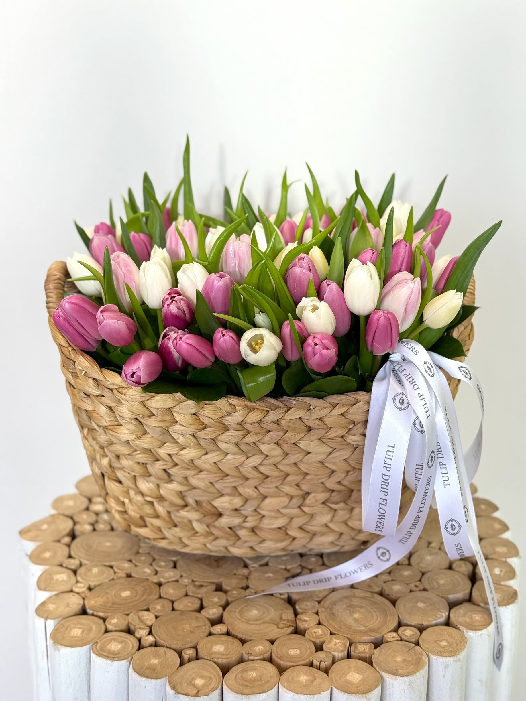 Basket of pink and white tulips with a ribbon