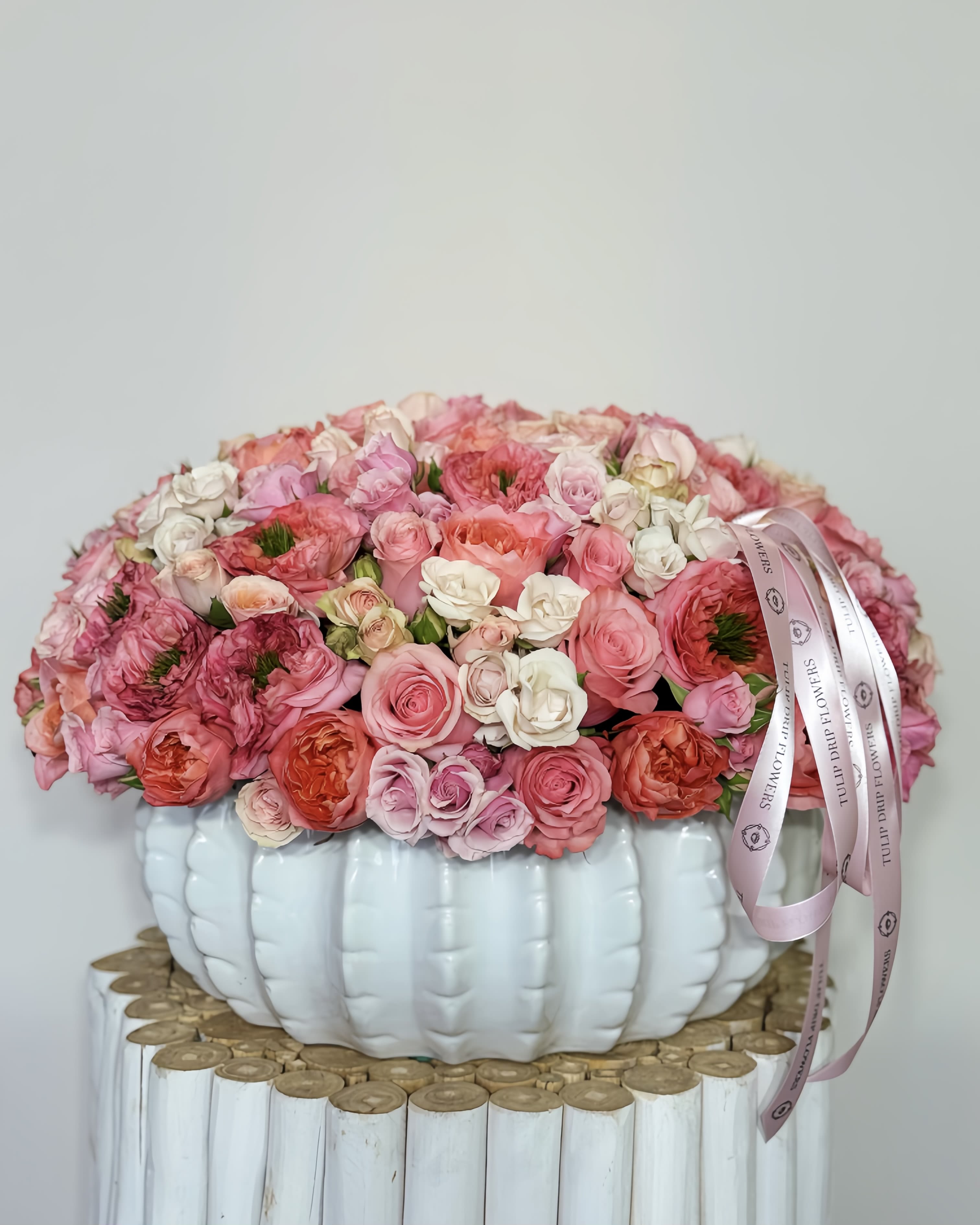 Pink and white rose arrangement in a white pumpkin-shaped vase with ribbon