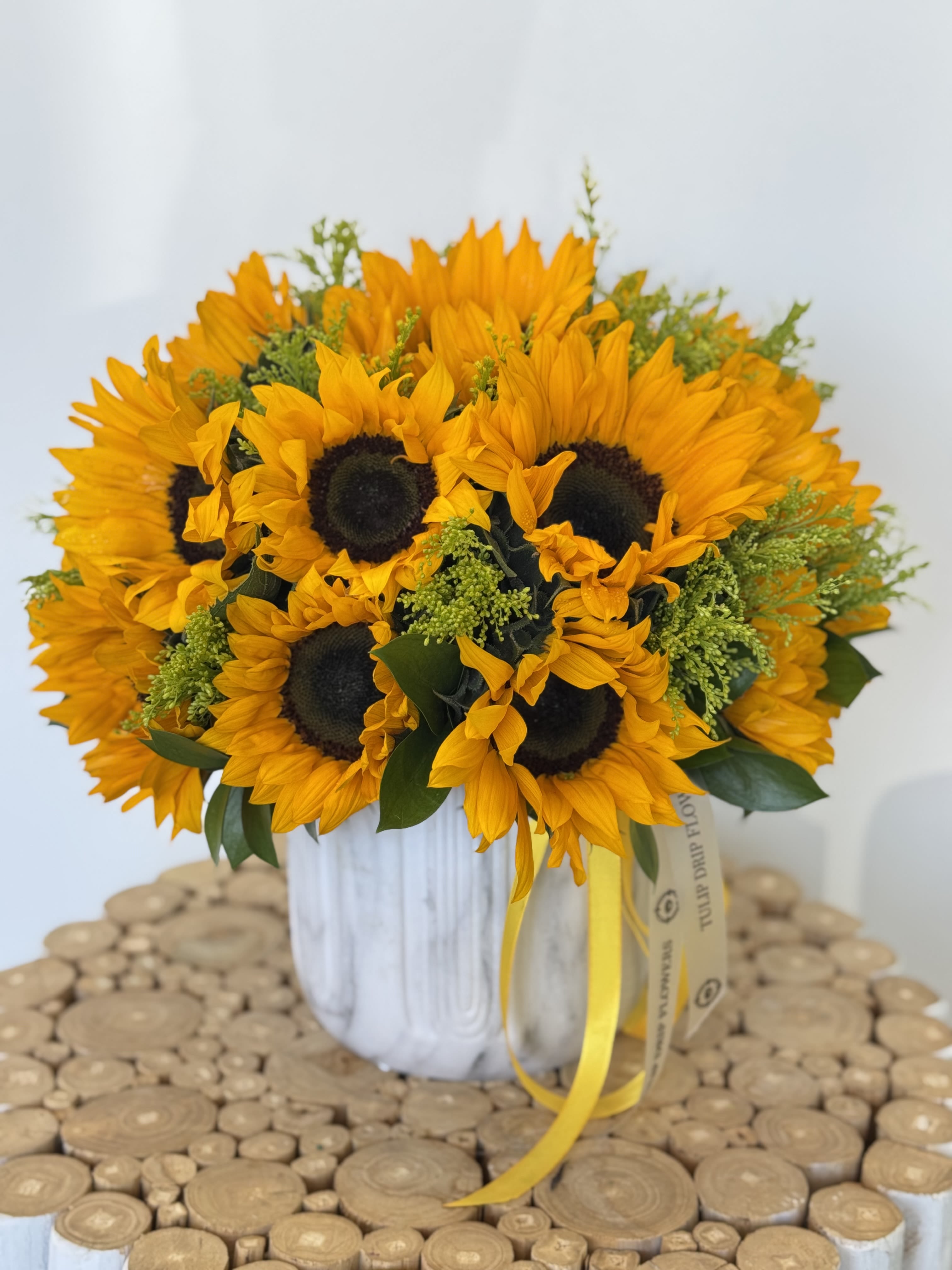 Bouquet of sunflowers in a white vase with a yellow ribbon