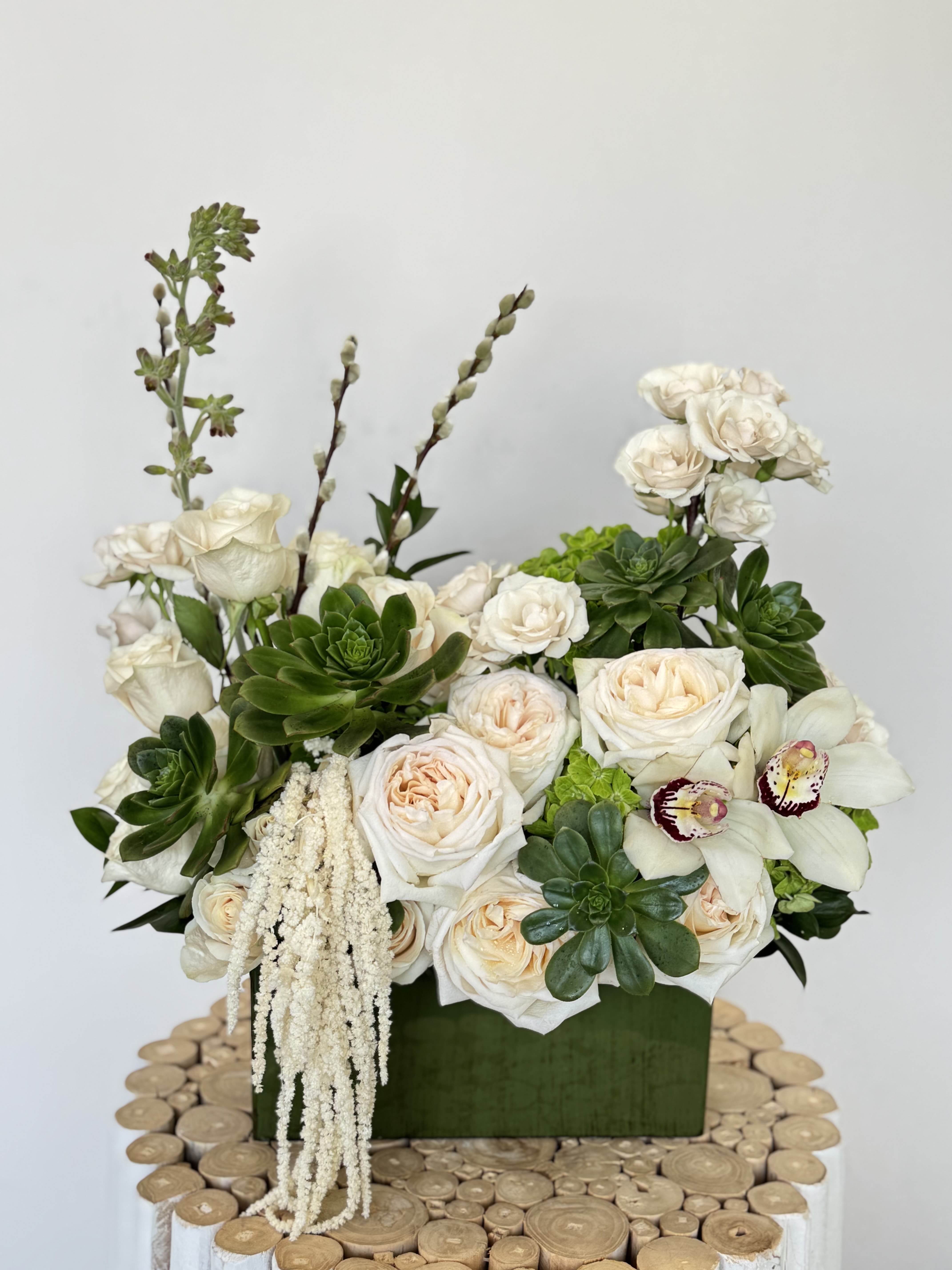 White roses and orchids in a green box with succulents