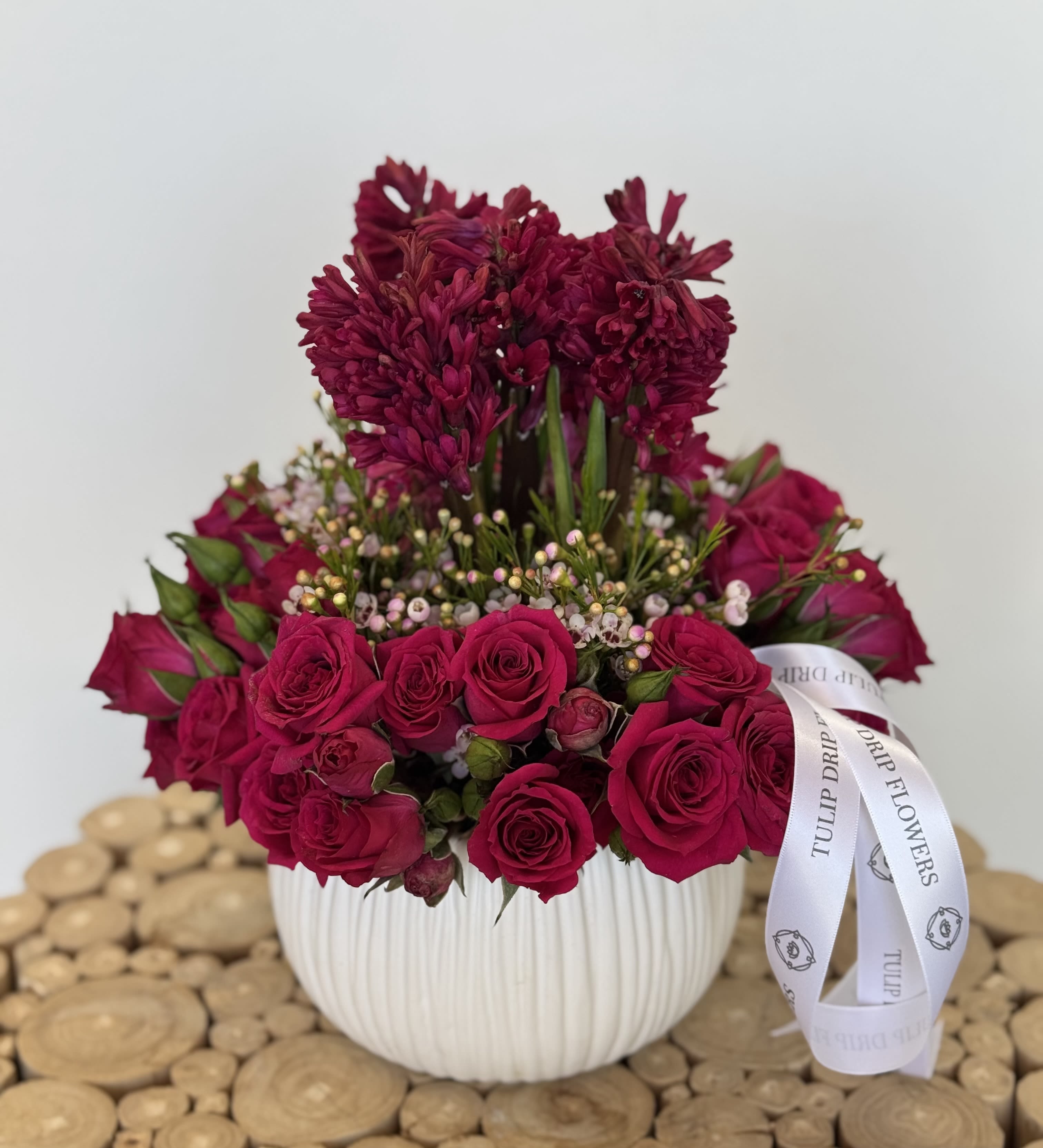 Magenta roses and dark pink blooms in a white ribbed vase