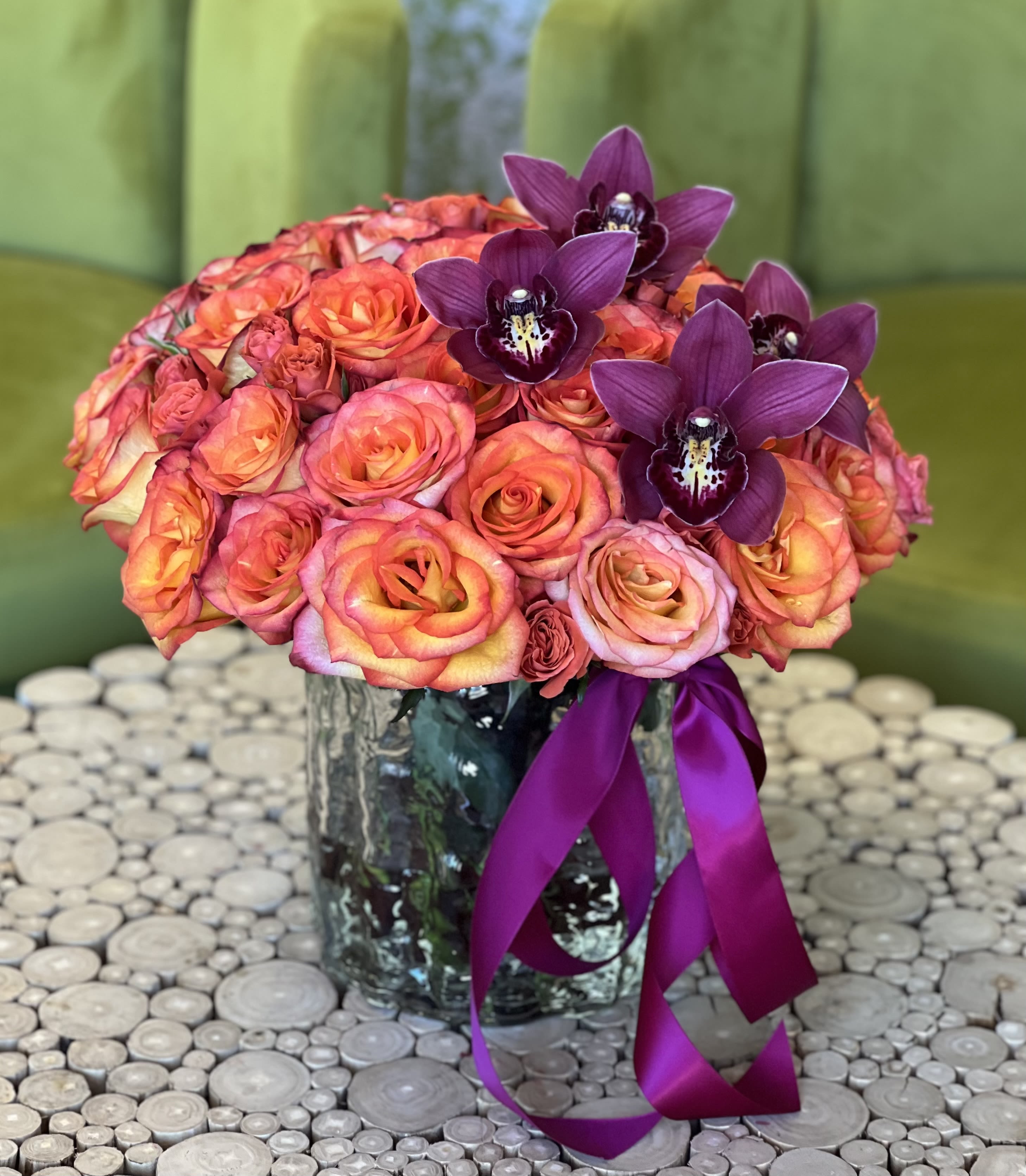 Bouquet of orange-pink roses and purple orchids in a glass vase