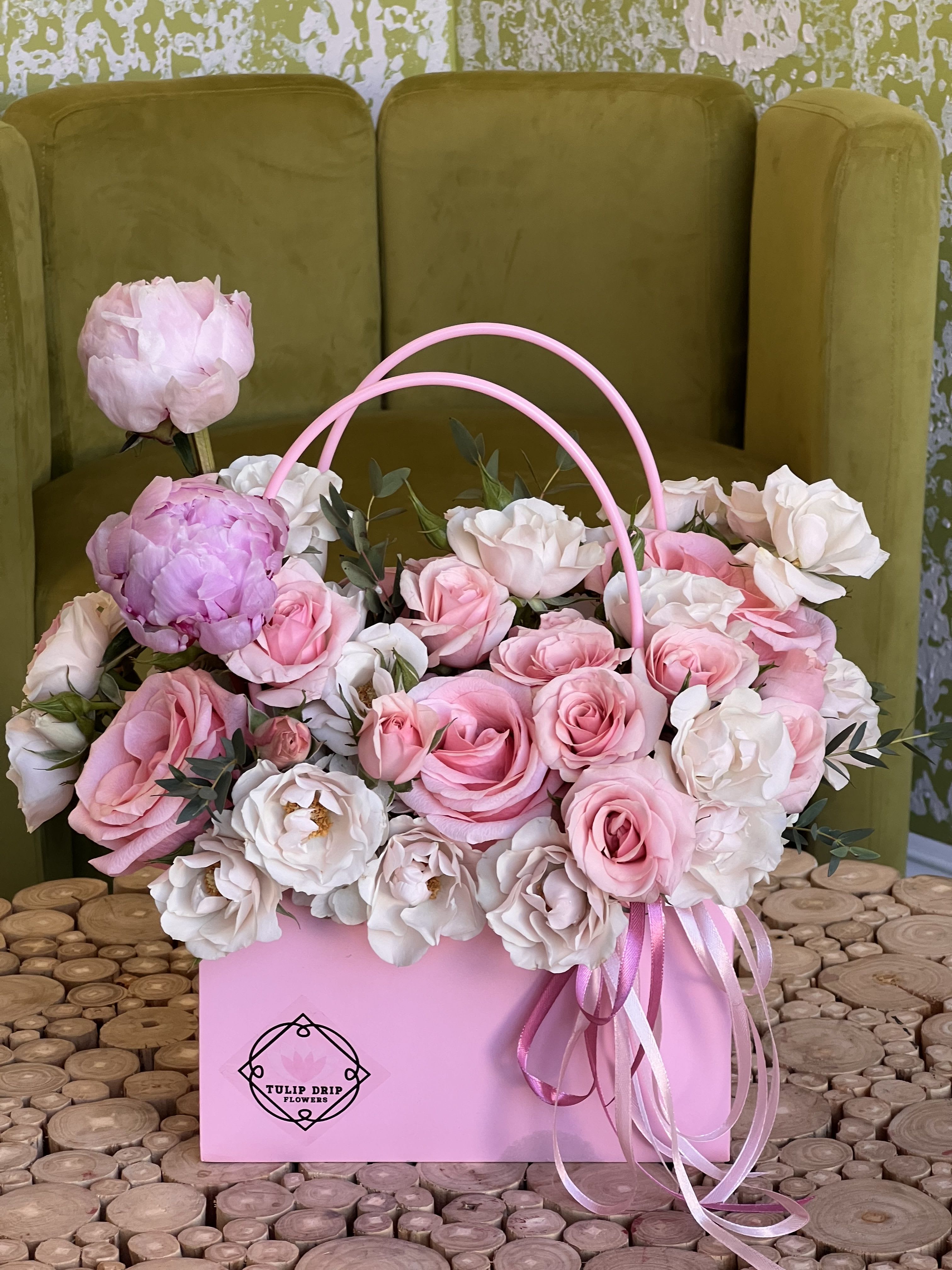 Pink and white roses arranged in a pink handled box with ribbon
