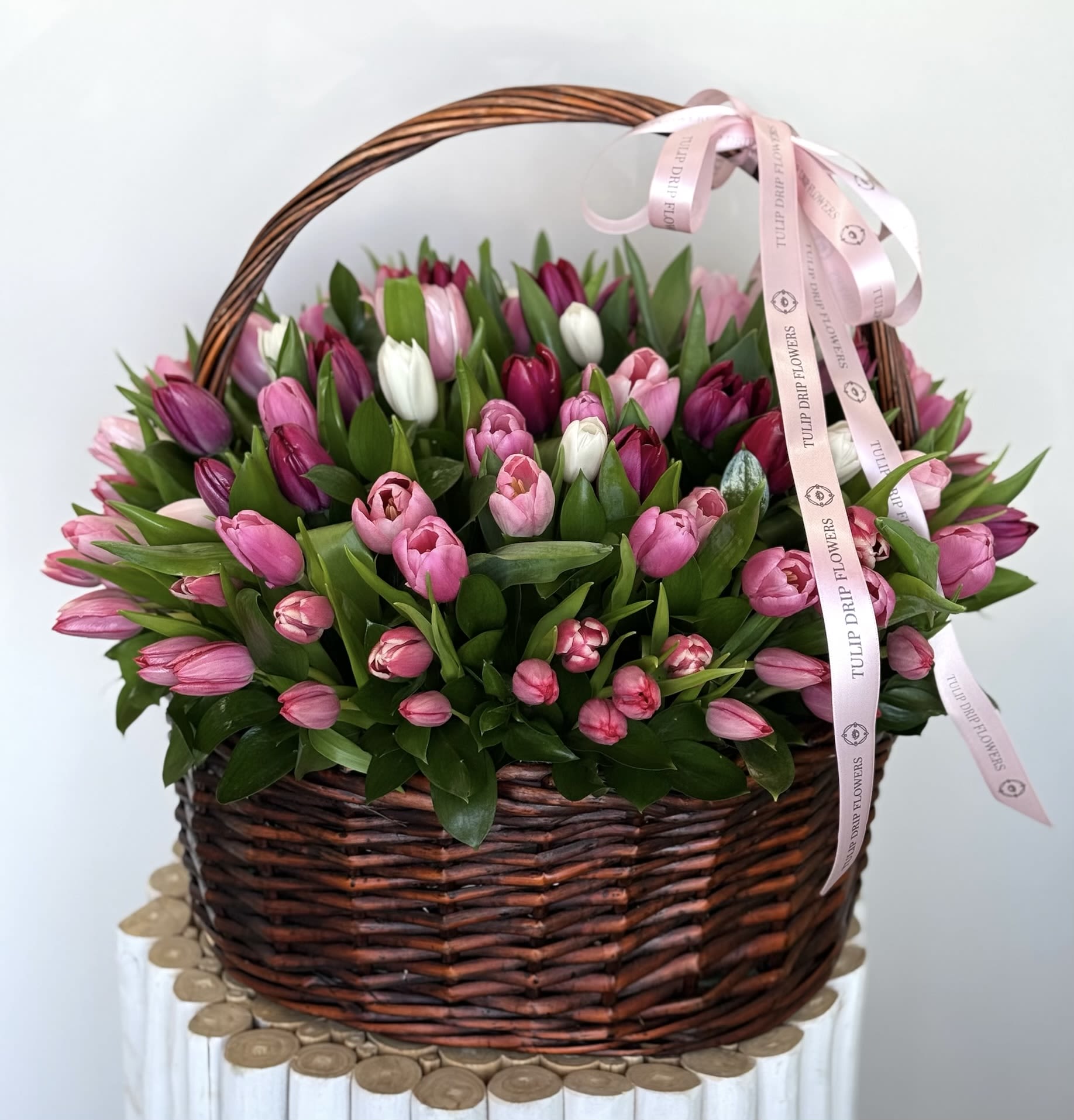 Basket of pink and white tulips with a pink ribbon bow