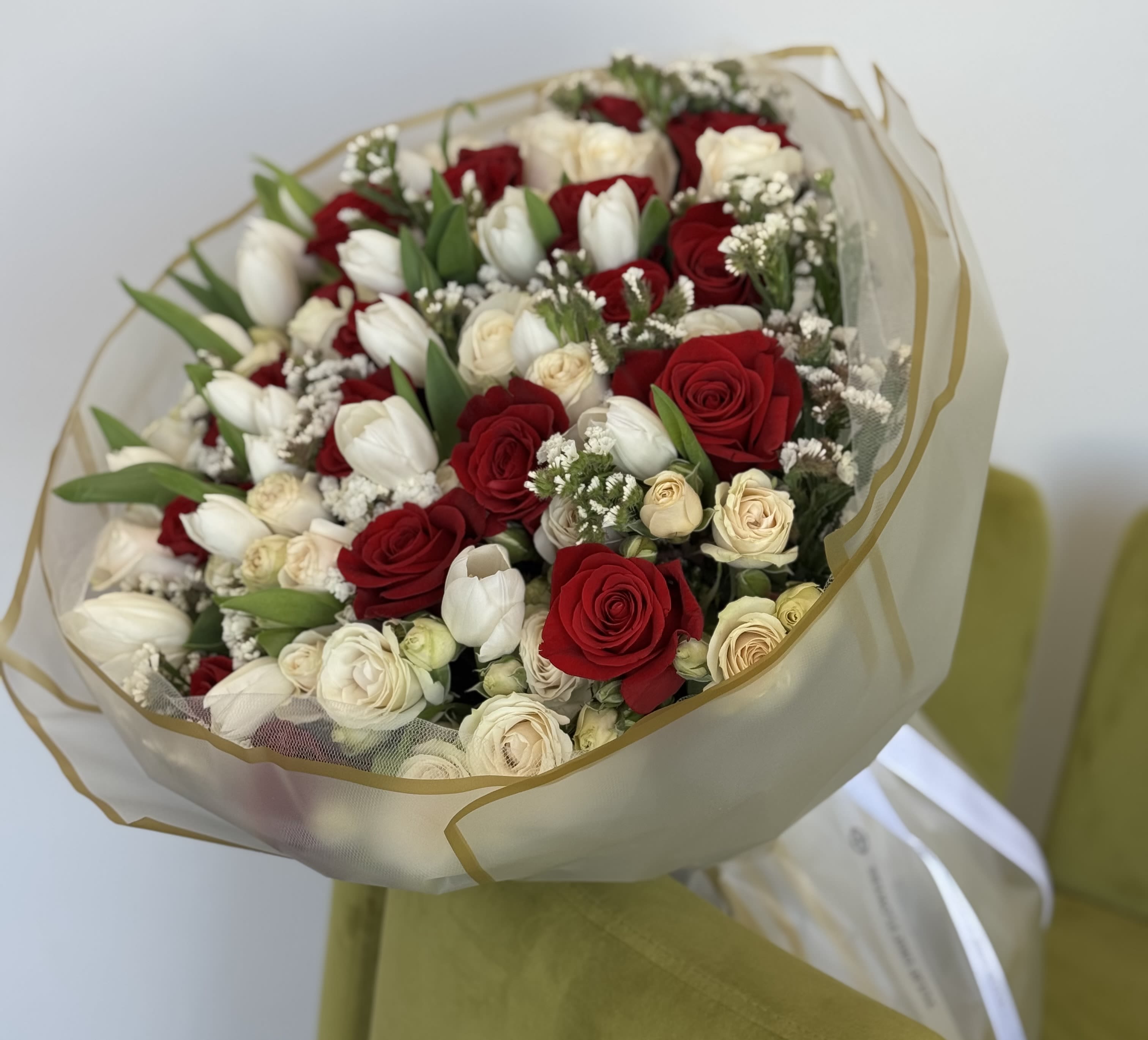 Bouquet of red and white roses with white tulips wrapped in sheer paper