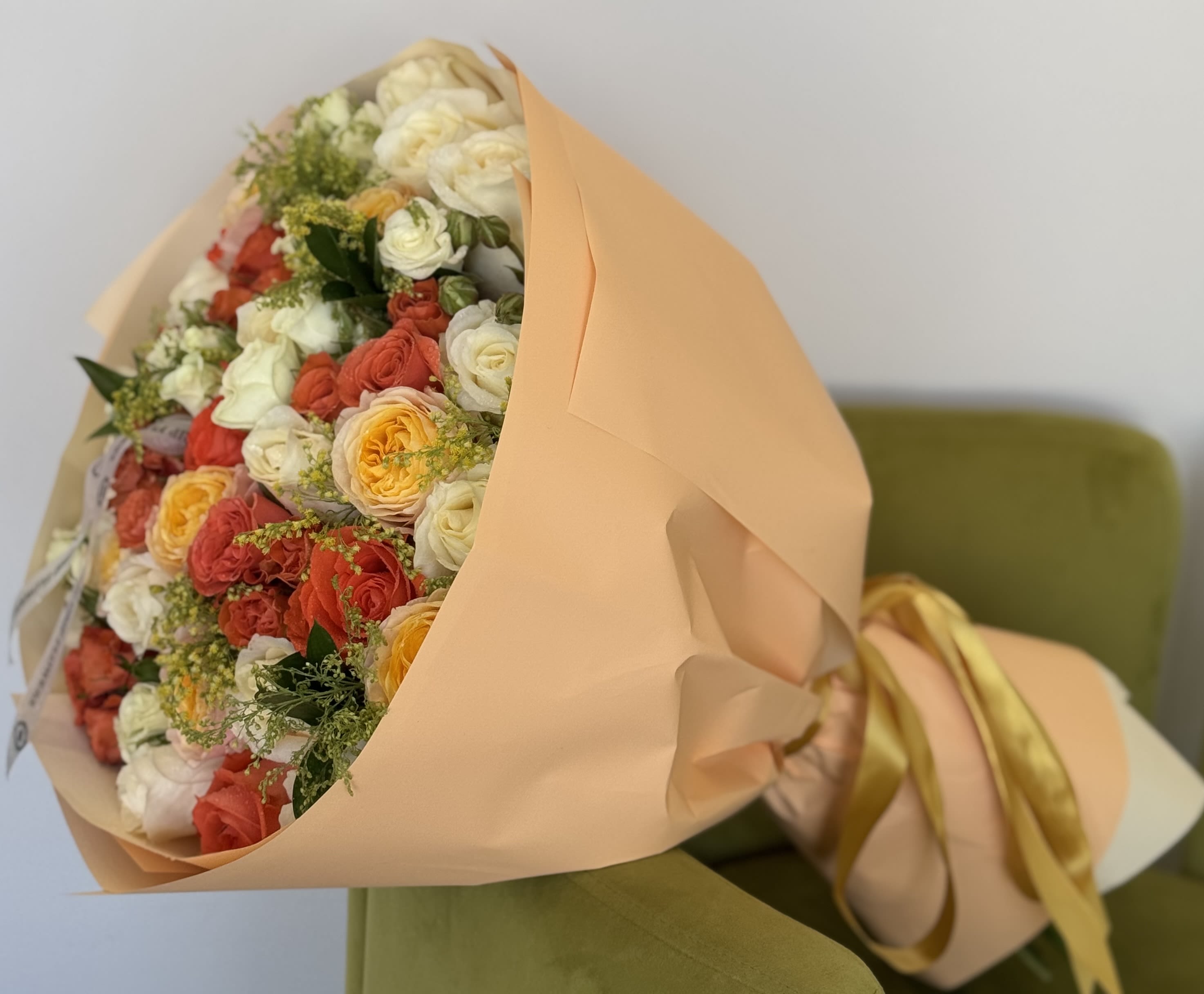 Bouquet of cream, coral, and yellow roses wrapped in peach paper