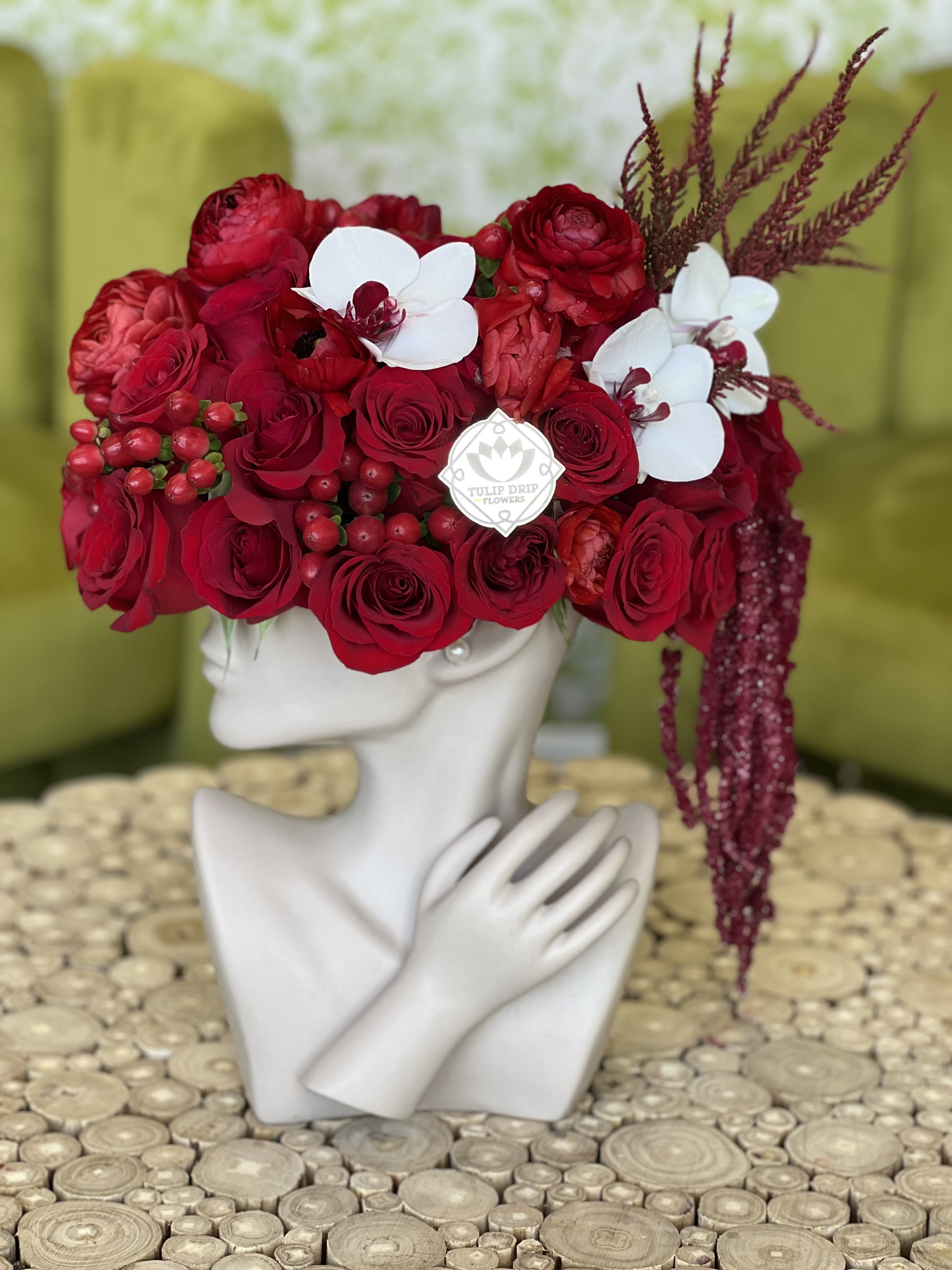 Red rose arrangement with white orchids on a mannequin head vase