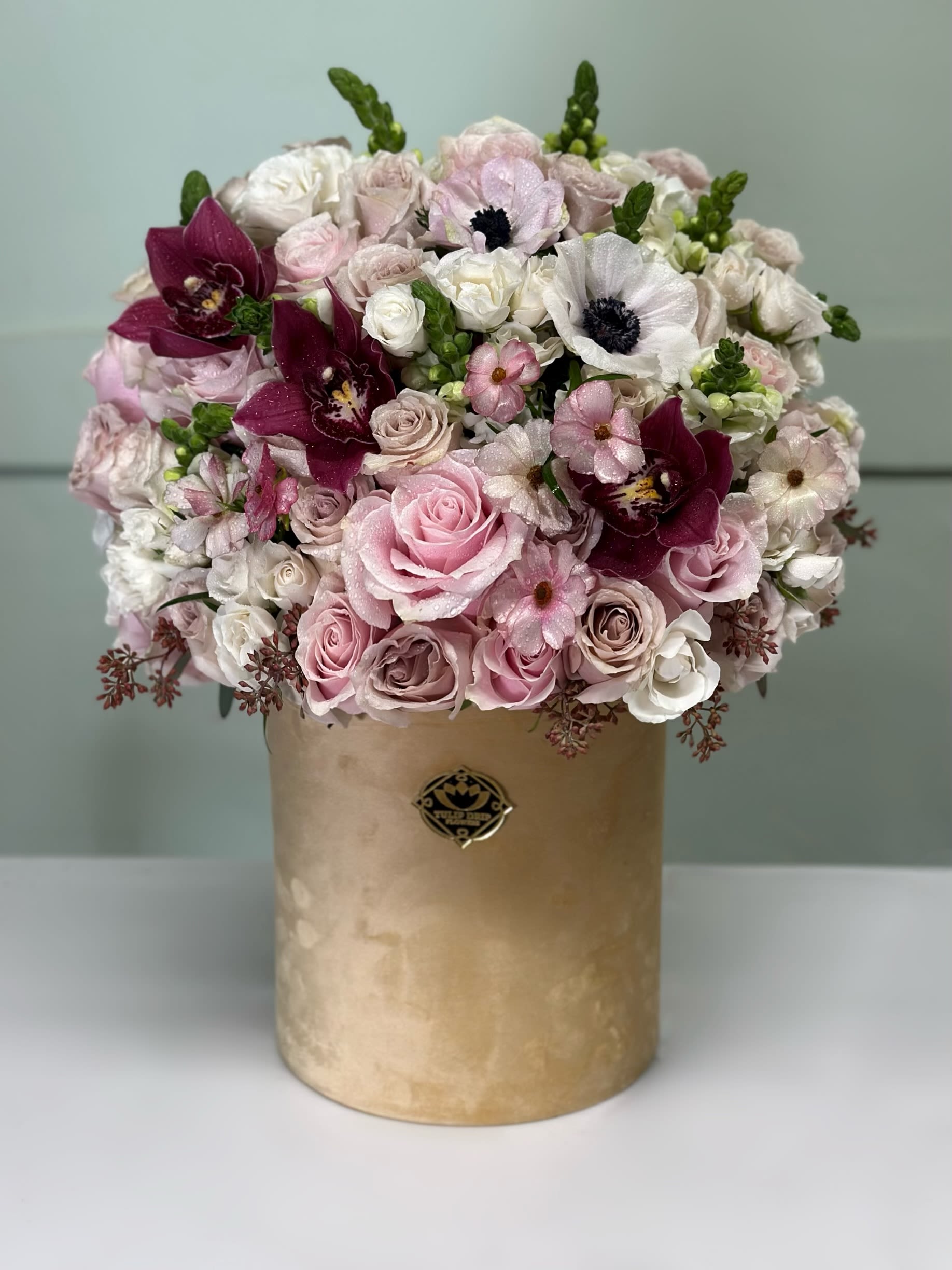 Pink and white bouquet in a gold cylindrical box