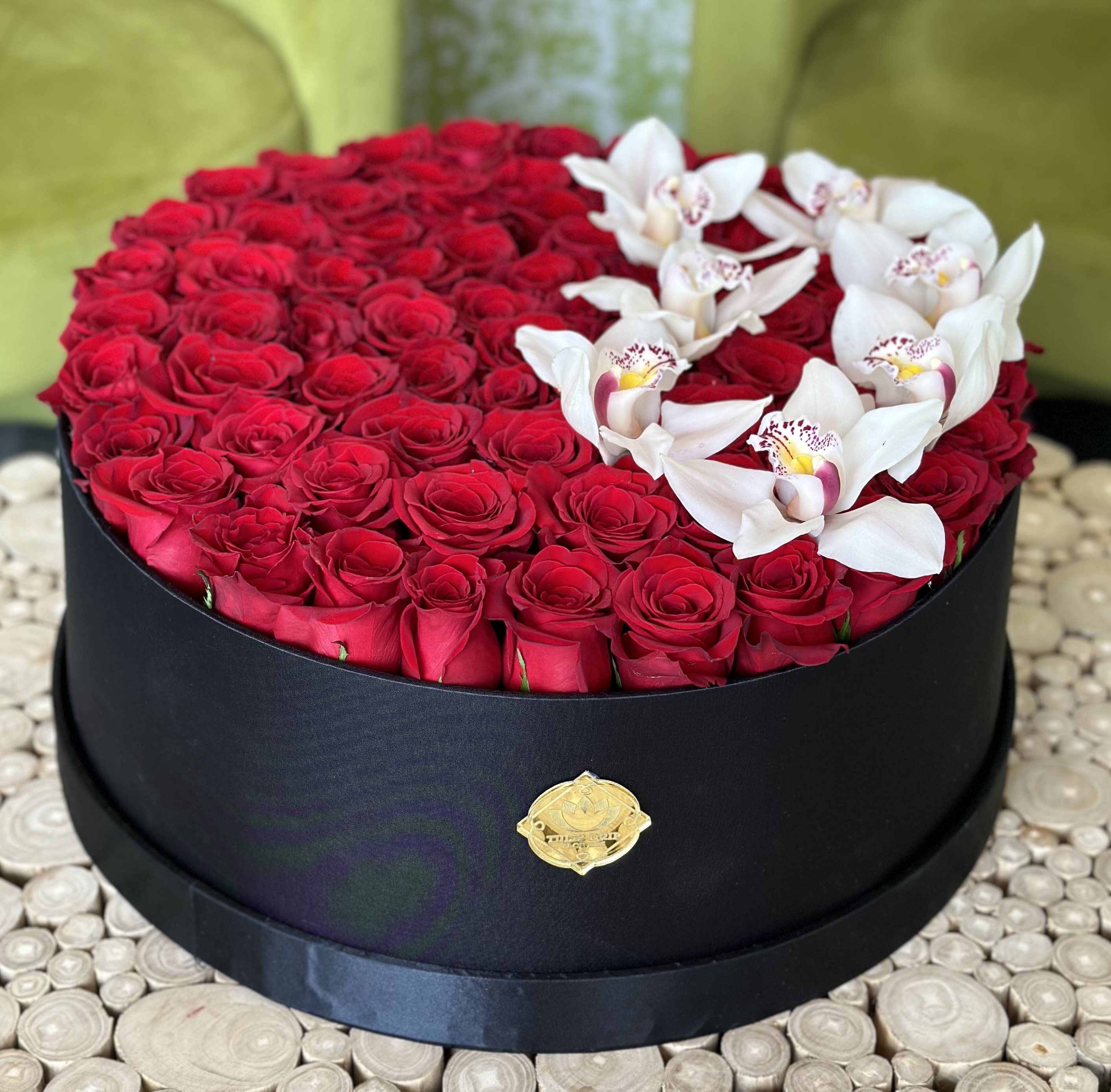 Round box of red roses topped with white orchids