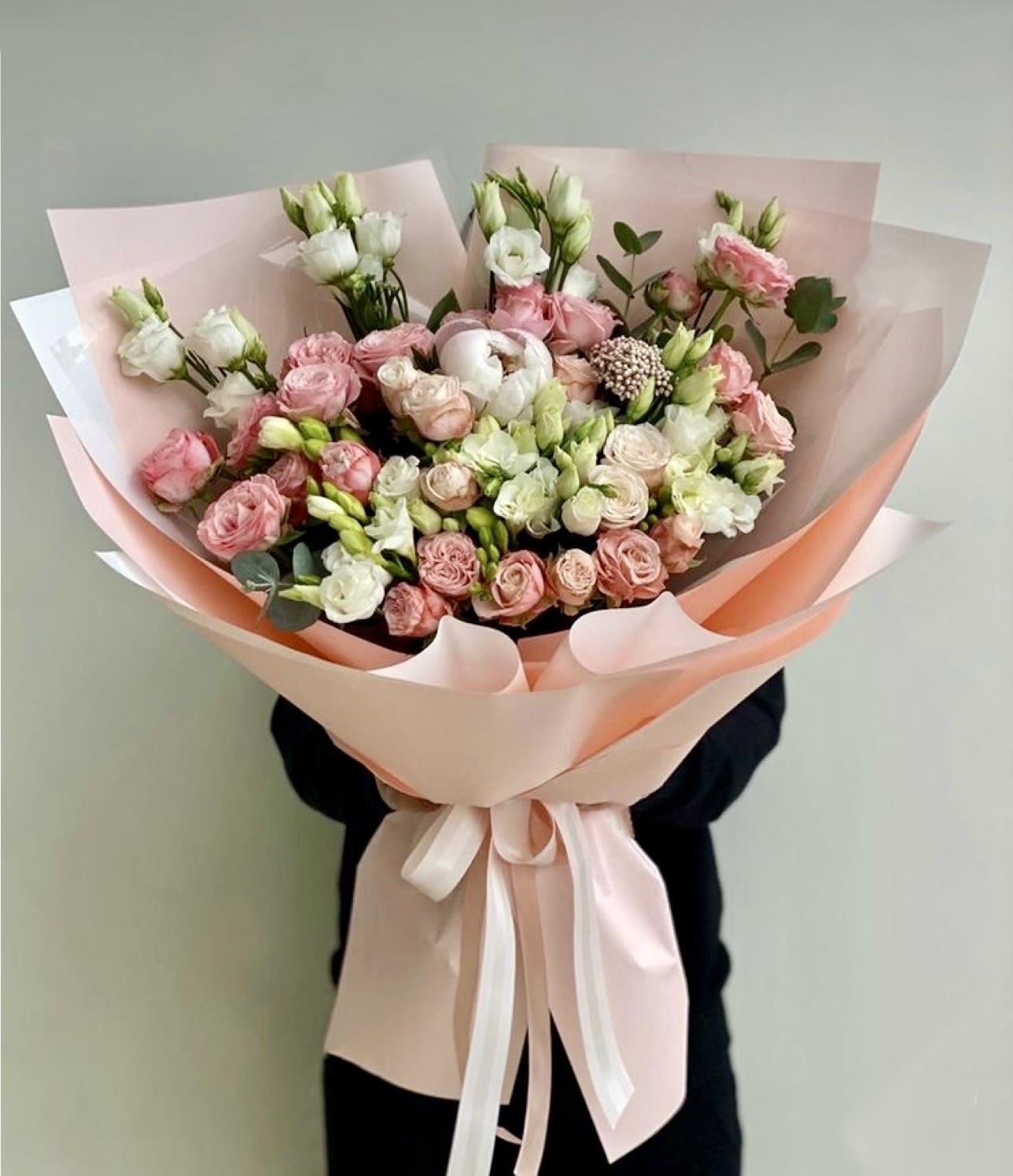 Bouquet of pink and white roses wrapped in pale pink paper