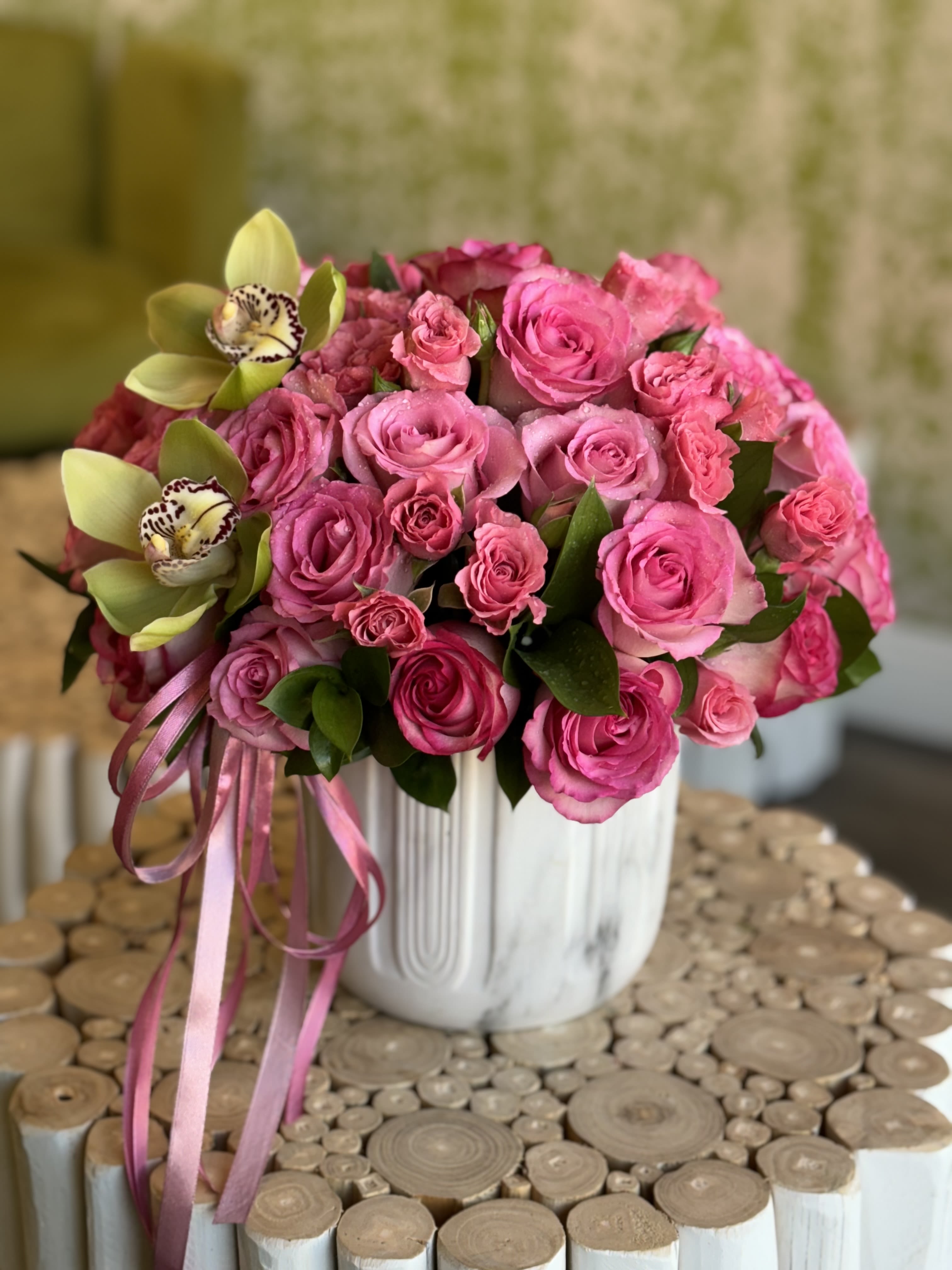 Pink rose bouquet with two pale green orchids in a white vase