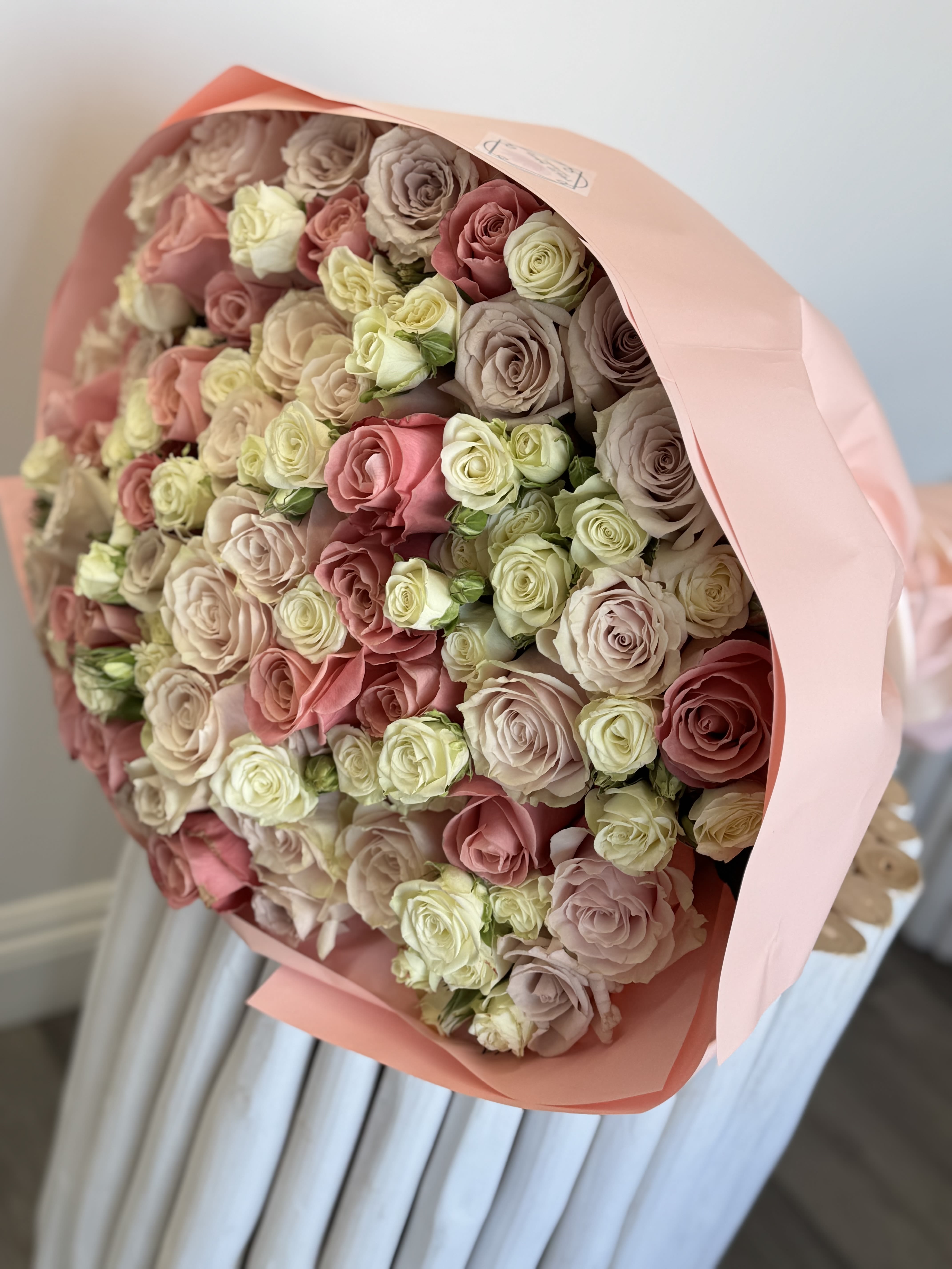 Peachy Cream Delight  - This stunning big bouquet blends peach, cream, and soft pink roses in a full, voluminous design. Wrapped in coral-toned paper, it’s the perfect floral gift to show your love and appreciation on Mother’s Day. THE IMAGE SHOWN REPRESENTS OUR PREMIUM SIZE ARRANGEMENT.  