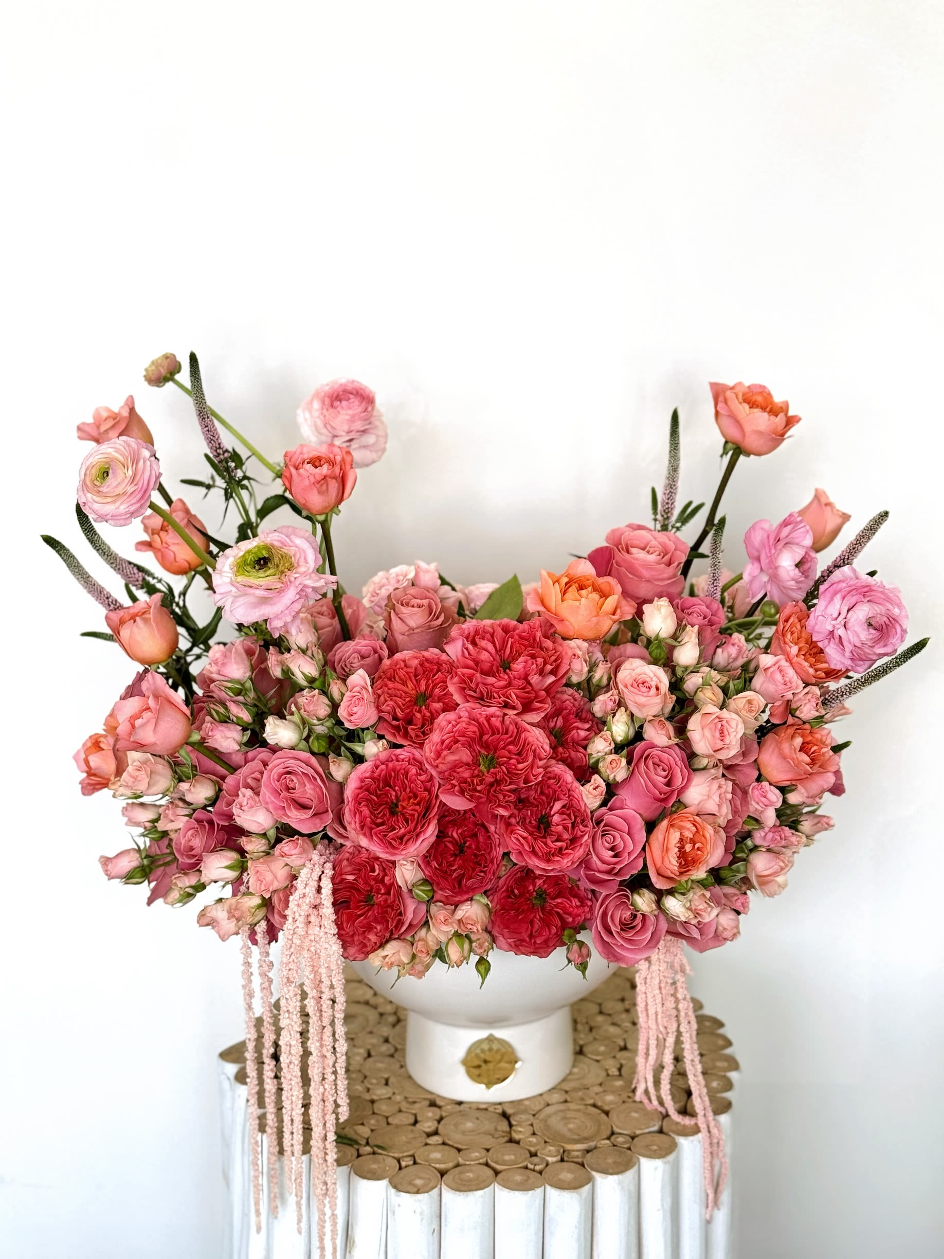 Large pink and coral floral arrangement in a white vase
