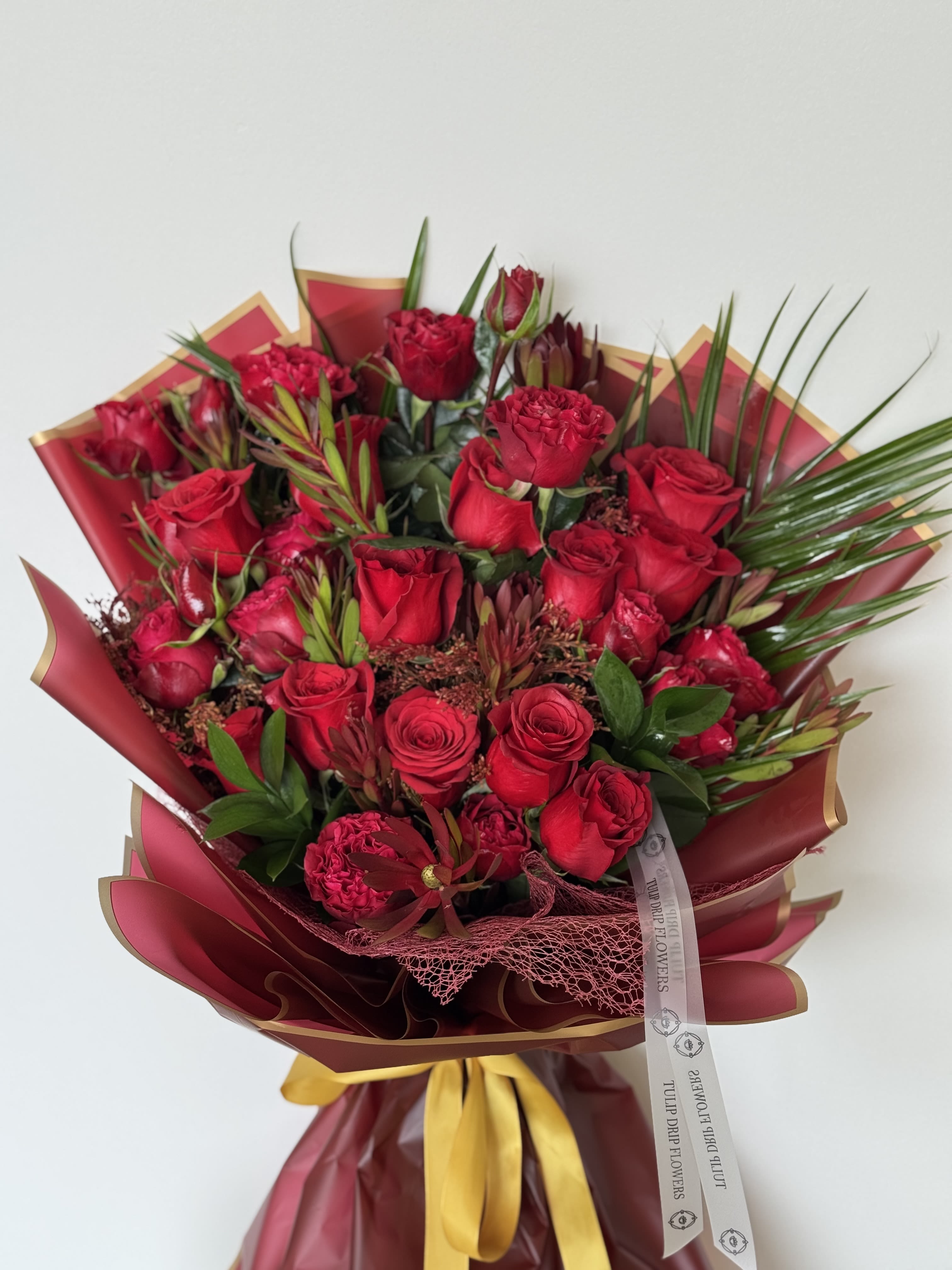 Bouquet of red roses and carnations wrapped in burgundy paper