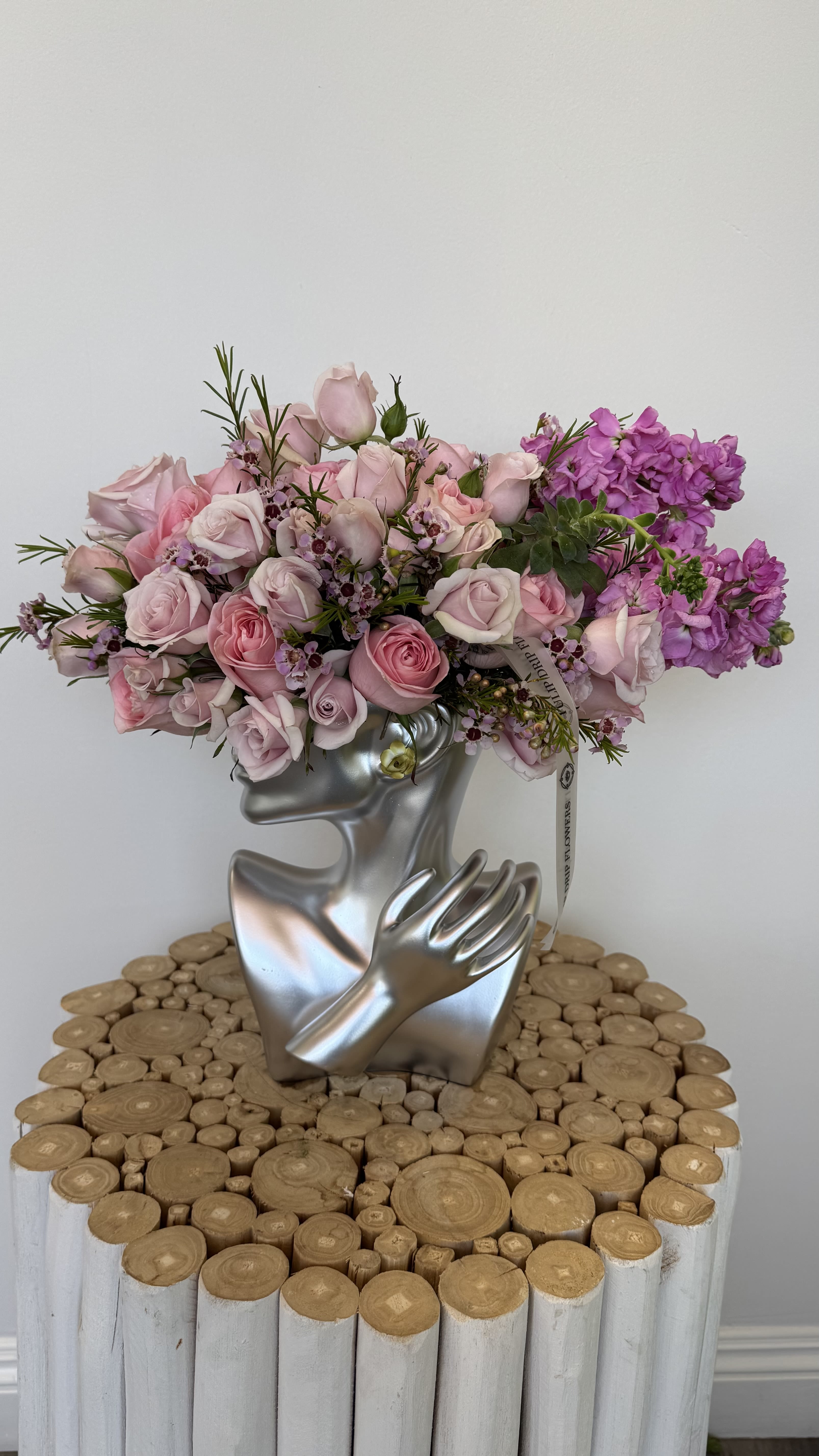 Pink and purple rose bouquet in a silver face-shaped vase
