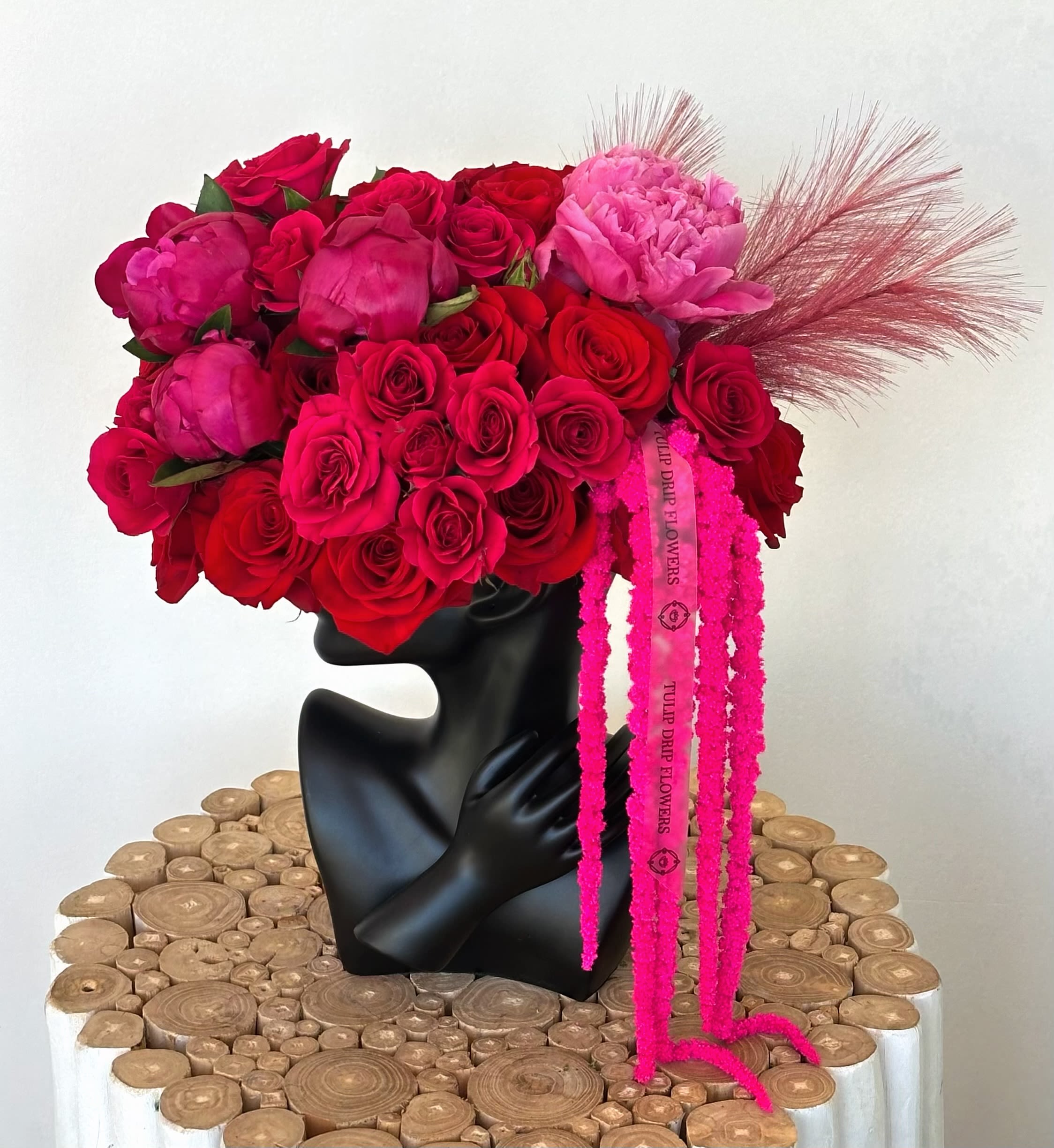 Bouquet of red and pink roses with peonies in a black vase