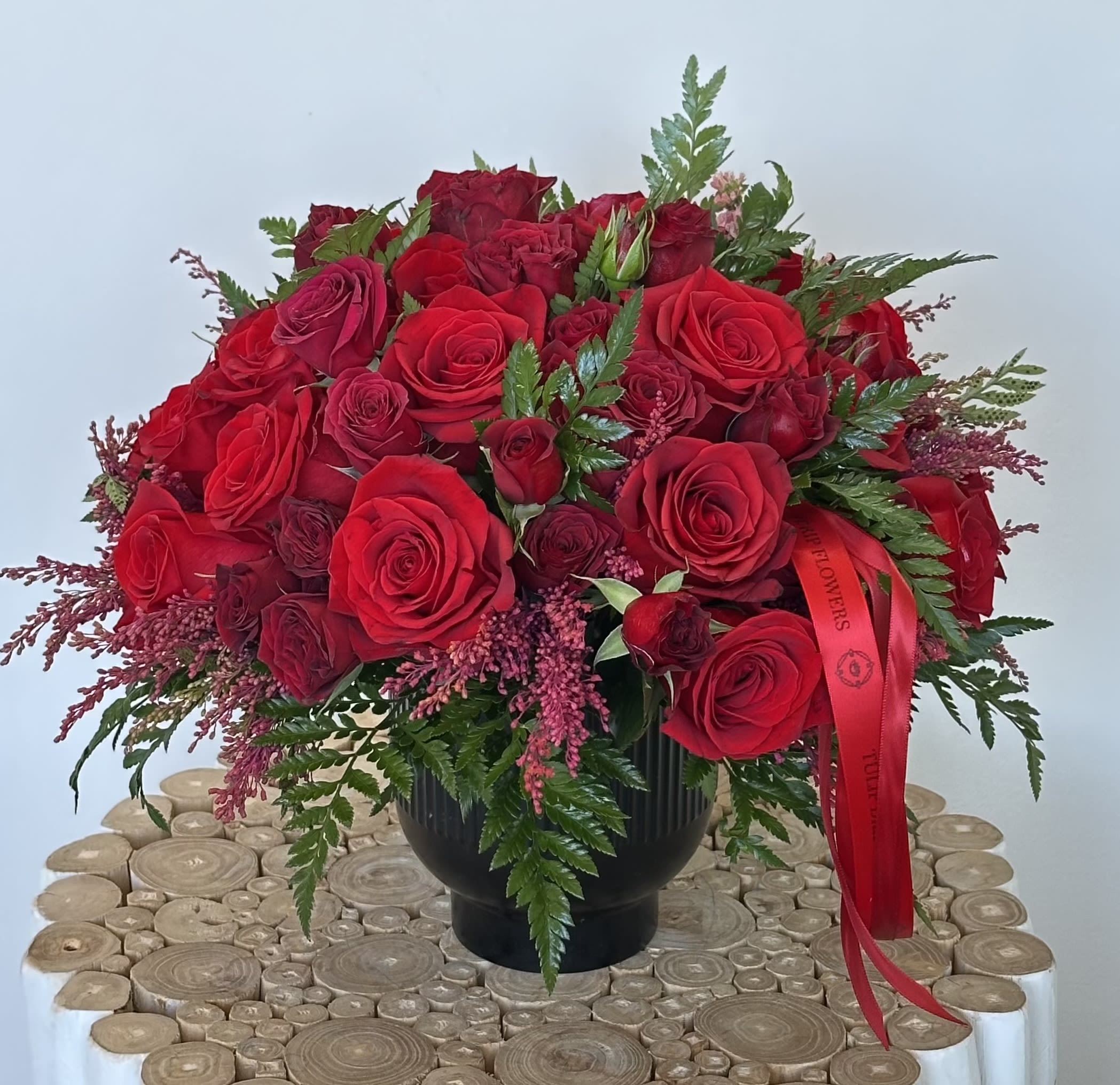 Red rose bouquet in a black vase with a red ribbon