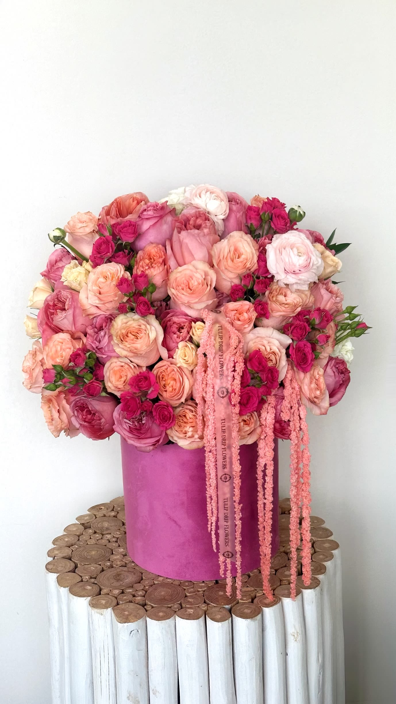 Pink and peach rose bouquet in a magenta hat box with trailing ribbons